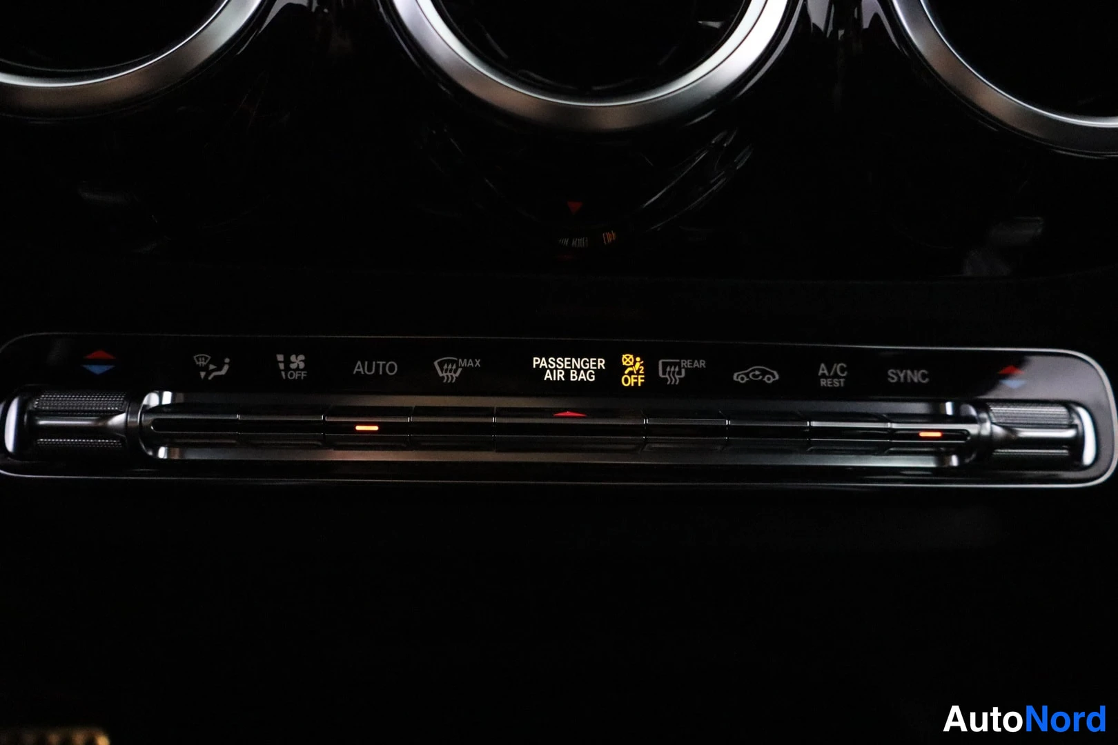 Muu: Auton ilmastointipaneelin napit (AUTO, MAX, REAR, A/C REST, SYNC) ja keltainen PASSANGER AIR BAG OFF -merkkivalo.