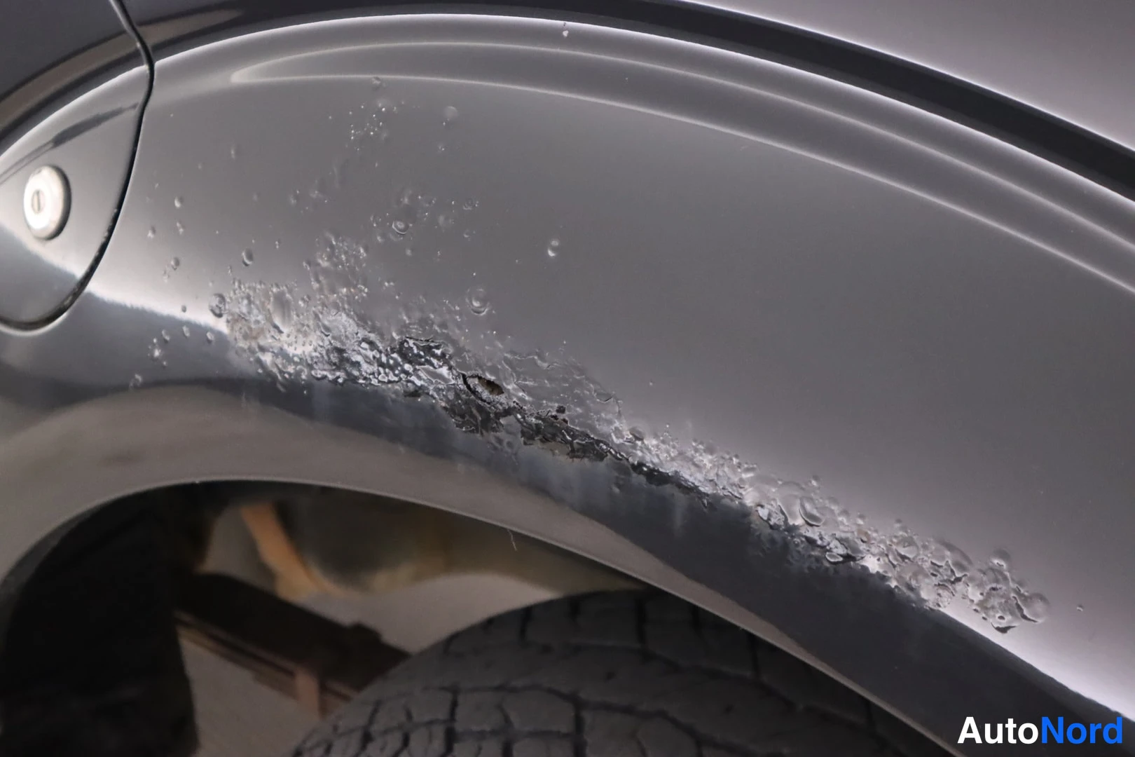 Sivulta: Close-up of rear wheel arch with bubbling and flaking paint along the arch edge, tyre visible below.