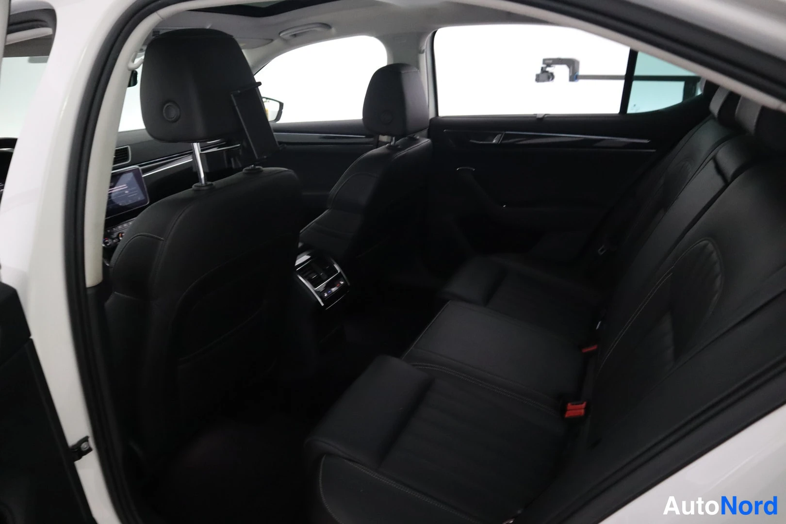 Takaistuimet: Skoda Superb 2020 takaistuimet mustat ja takakonsolin napit, kuvattuna takaoven kohdalta