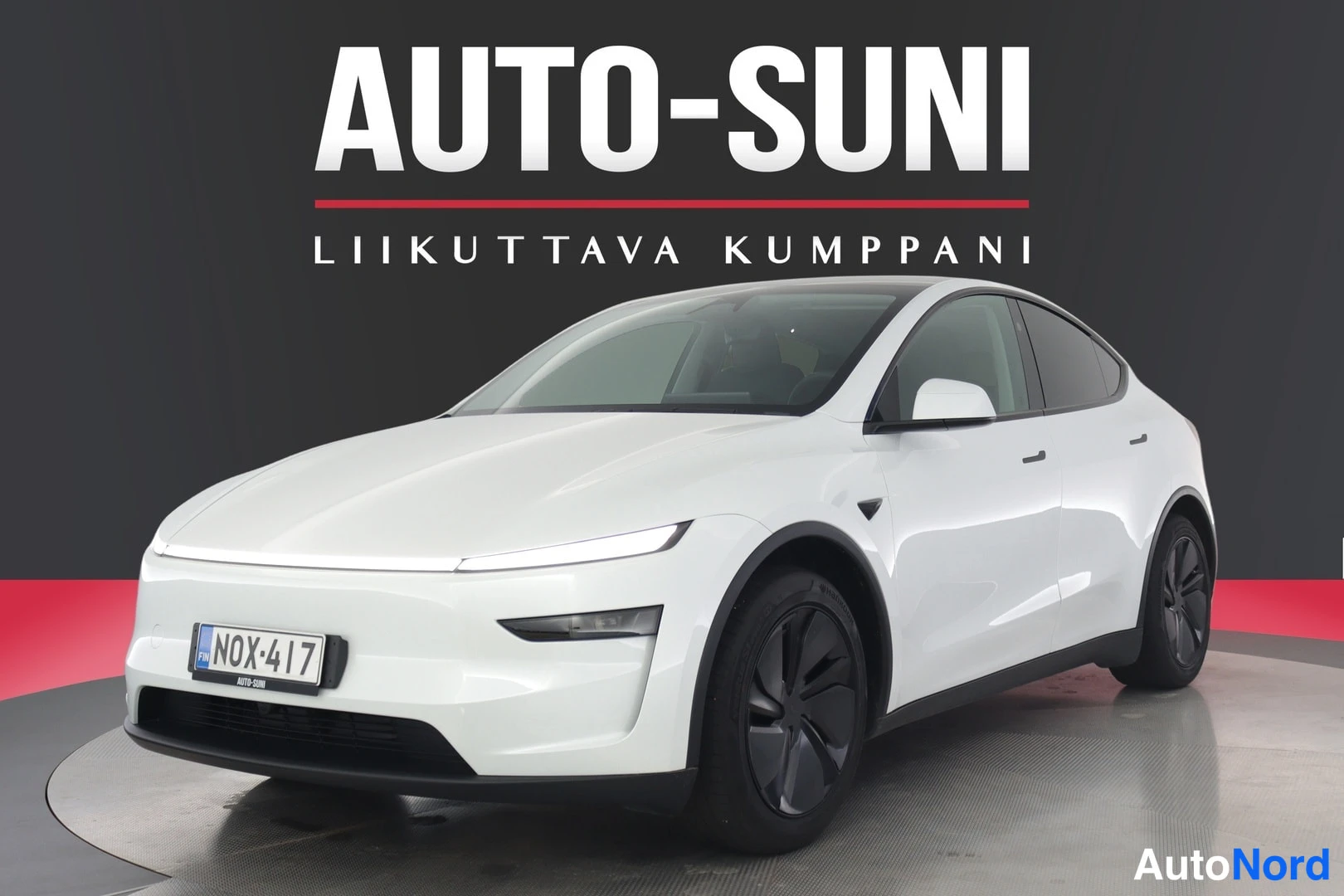 Etuviisto, nokka vasemmalle: Valkoinen Tesla Model Y etuviistöstä vasemmalta, rekisterikilpi näkyvissä.