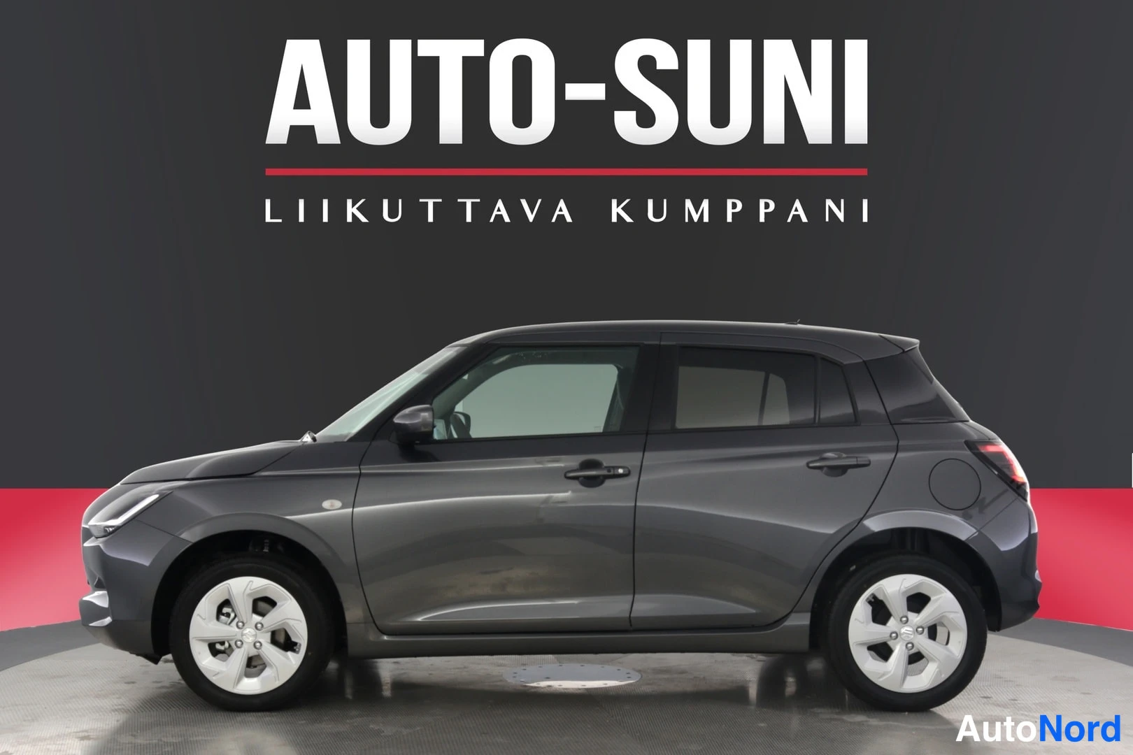 Sivulta: Kuvassa on automallinen tummansininen Suzuki Swift -mallinen auto. Autoa kuvattu profiilista. Autossa on sähkötoimiset ikkunat ja peilit sekä keskuslukitus. Kuv