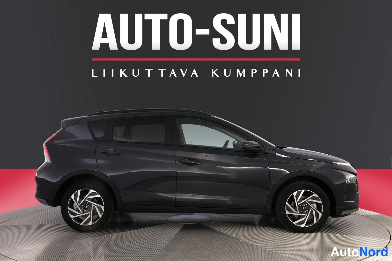Sivulta: Auton sivuprofiili: tummanharmaan tila-auton molemmat kyljet ja pyörät kuvassa, tumma tausta ja AUTO-SUNI-teksti ylhäällä.