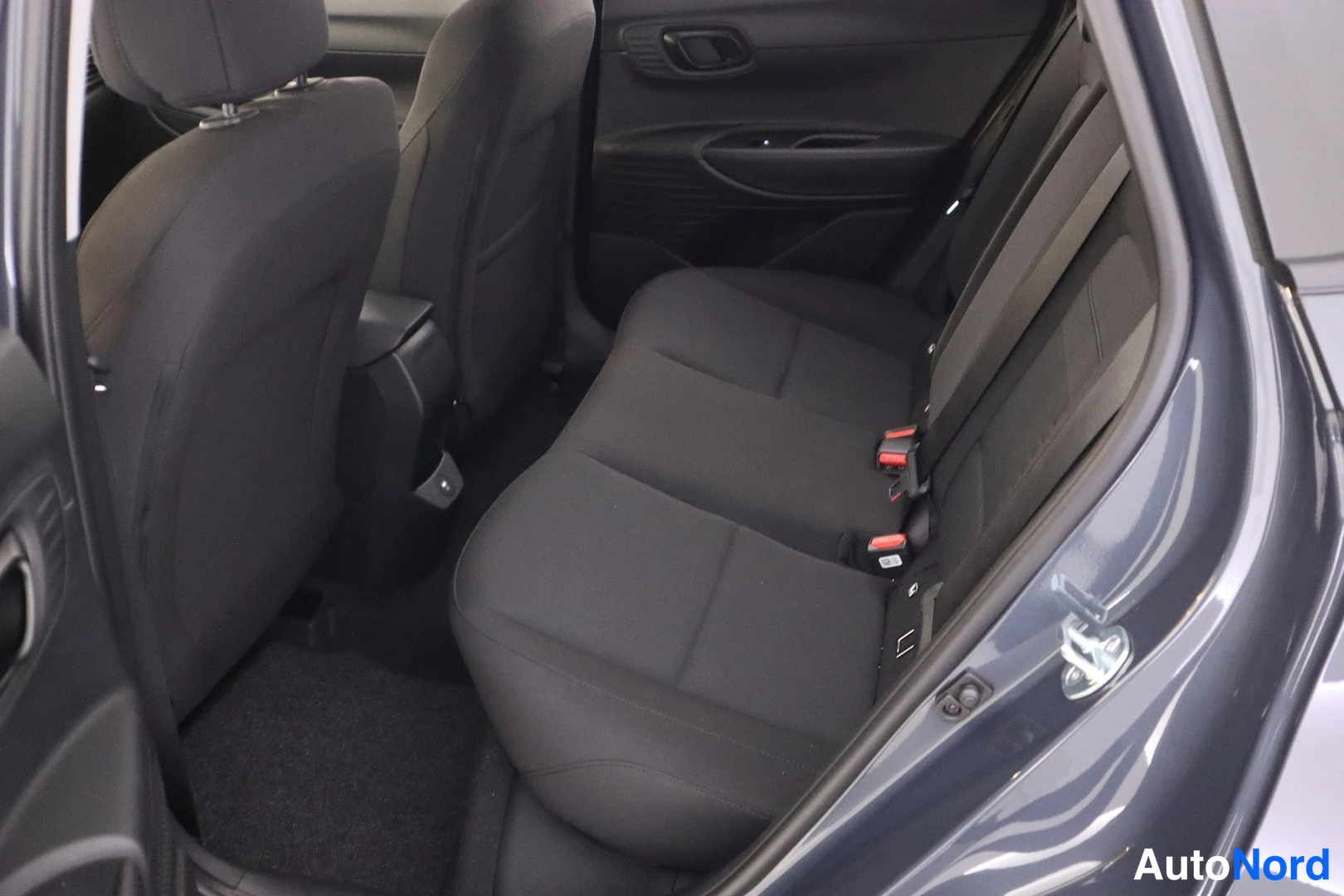 Takaistuimet: Takapenkit: kolme istuinta tummanharmaassa kankaassa. Turvavyöt ja ISOFIX-kiinnityspisteet näkyvät.