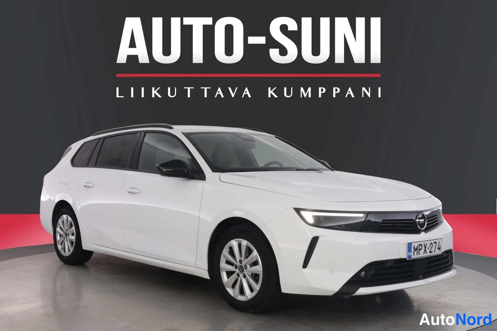 Etuviisto, nokka oikealle: Valkoinen farmarimallinen henkilöauto kolmivartalon etuviistosta oikealta, rekisteritunnus, kuvattuna studiotaustaa vasten.