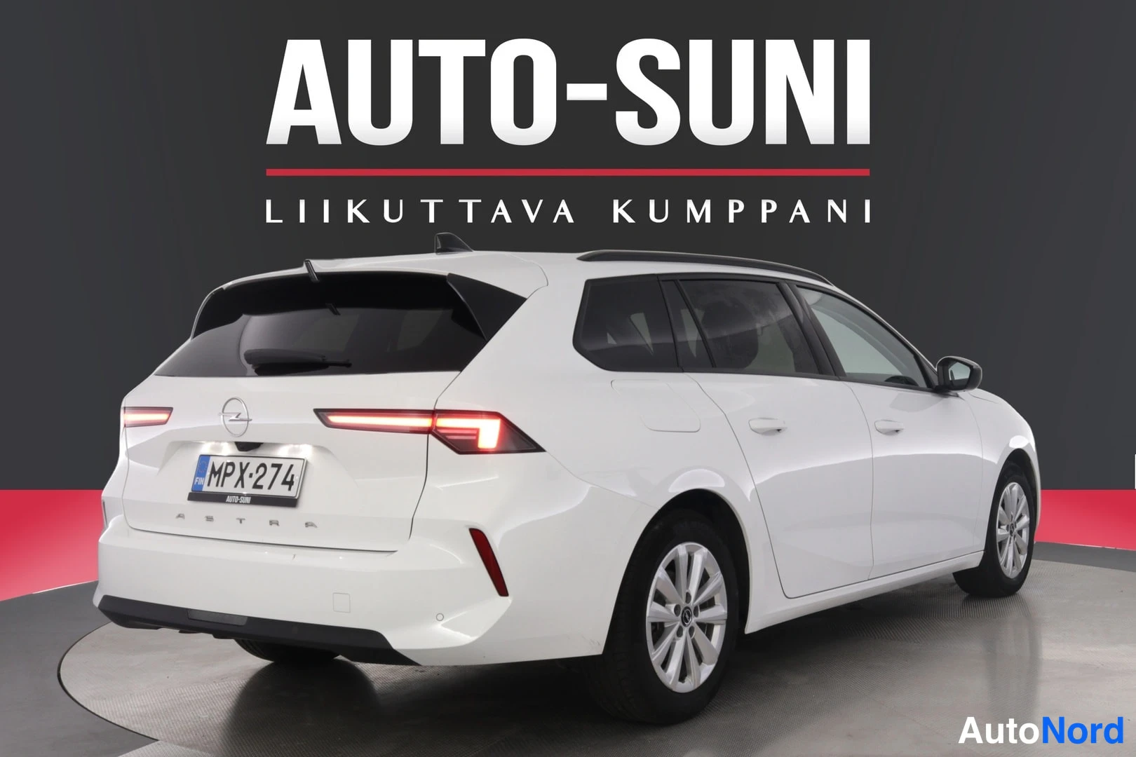 Takaviisto: Valkoisen Opel Astra -farmarin takaviisto, perä ja rekisterikilpi näkyvissä.