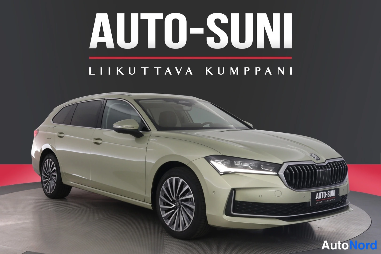 Etuviisto, nokka oikealle: Vihertävänbeige Skoda Superb -farmari etukulmasta, keulagrizzi ja vasen kylki näkyvissä studiokehässä.