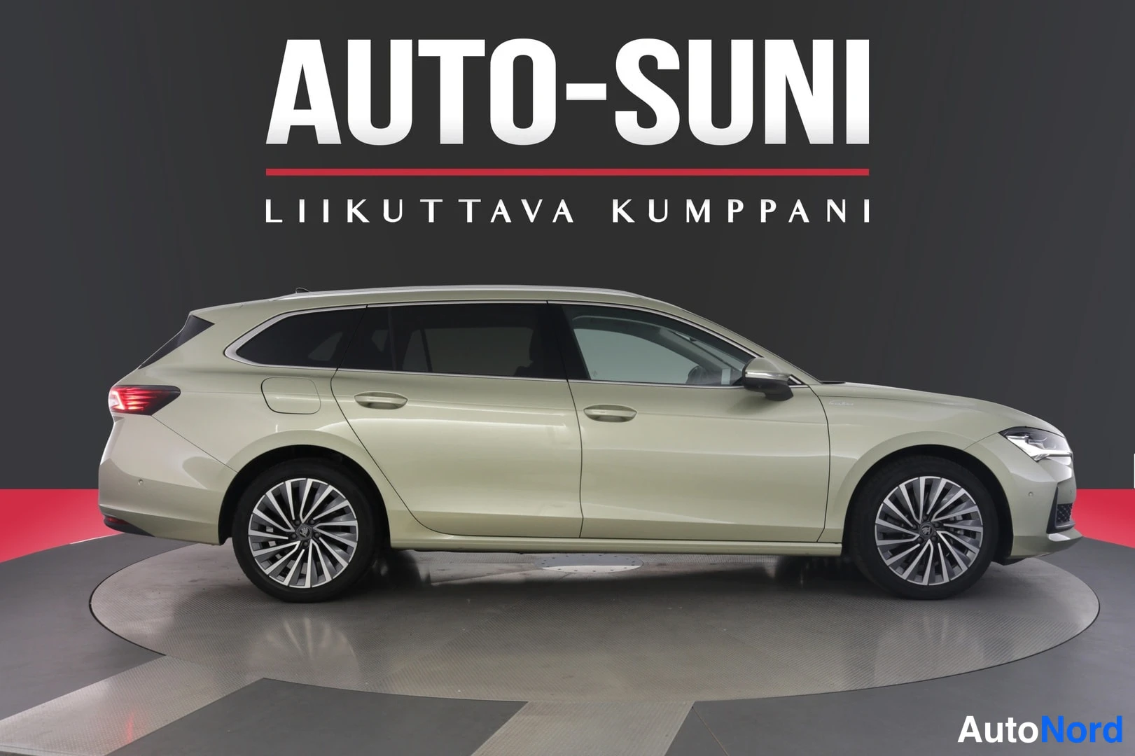 Sivulta: Vihertävänbeige Skoda Superb -farmari sivulta vasemmalta, takavalot ja molemmat pyörät erottuvat studiokehässä.