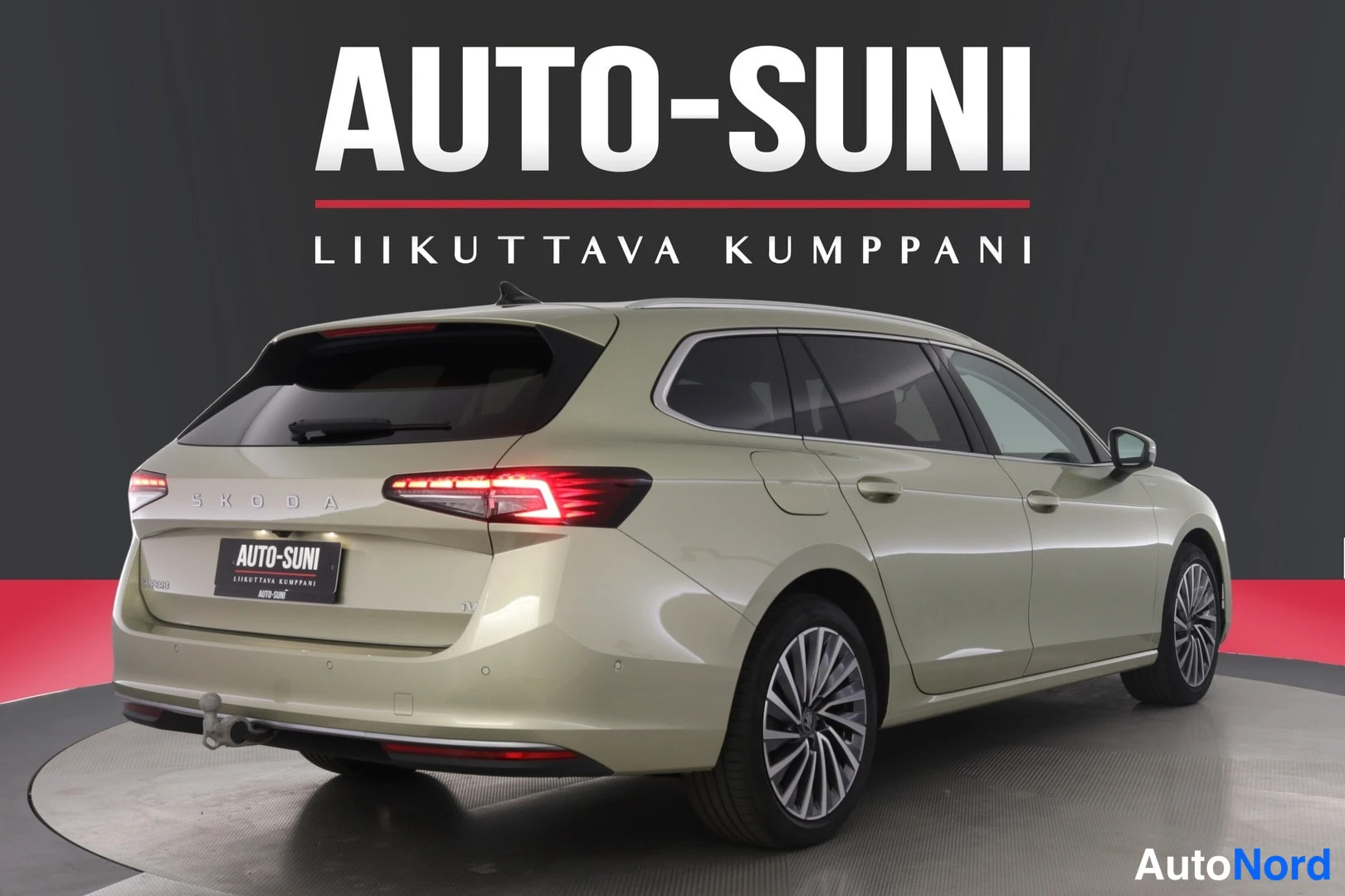 Takaviisto: Vihertävänbeige Skoda Superb -farmari takakulmasta, takavalot ja perkeli näkyvissä studiokehässä.