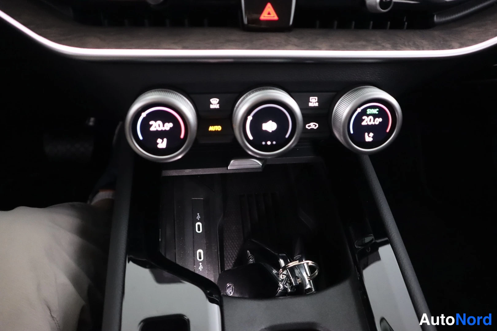 Yksityiskohta: Close-up of the center console climate controls featuring three circular digital dials. The outer dials are set to 20.0°C, showing 'AUTO' and seat heating icons