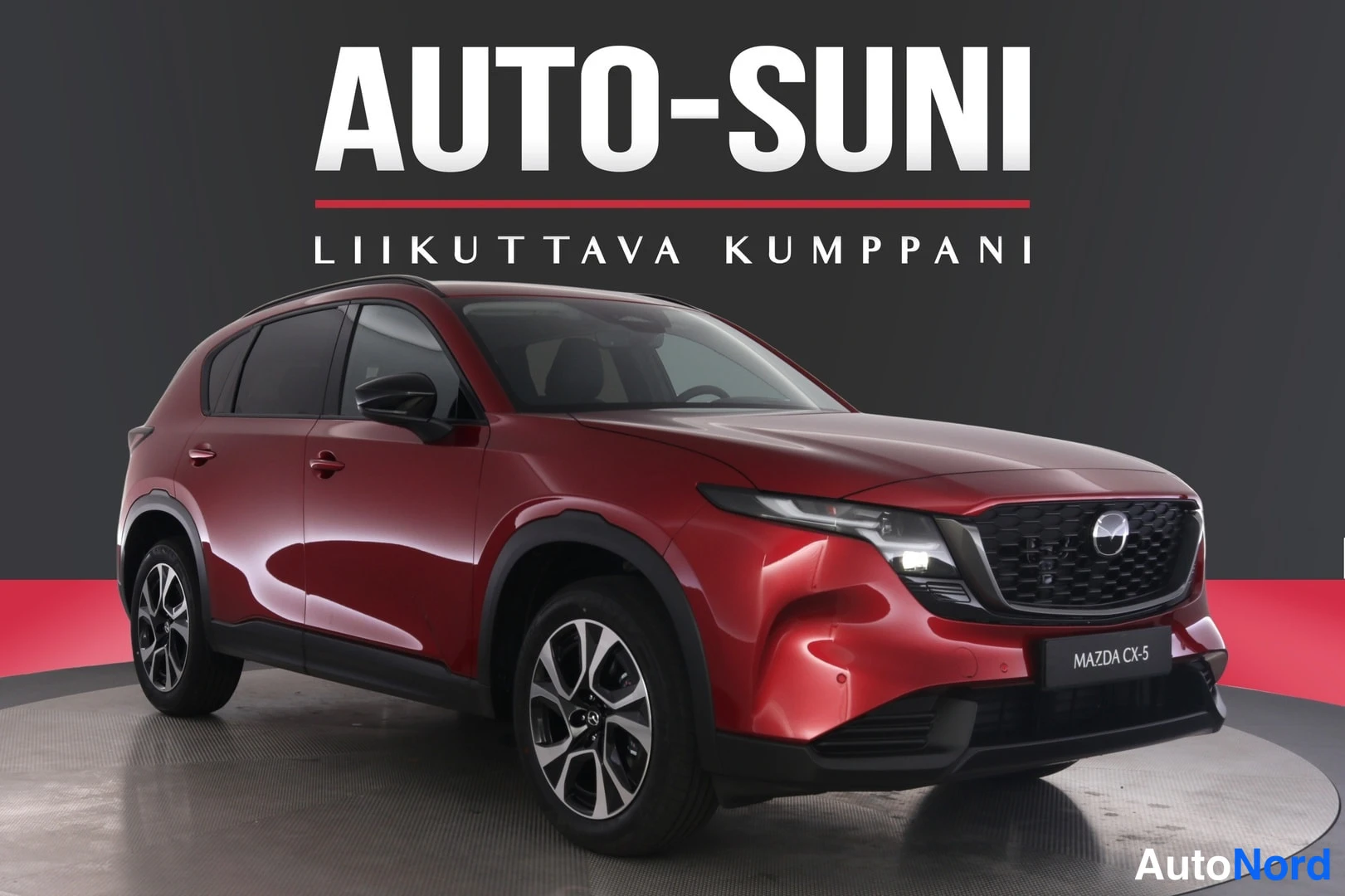 Etuviisto, nokka oikealle: Punainen Mazda CX-5 -mallinen auto kuvattu etu kolmasosan kulmasta, keulaverso ja vasen kylki näkyvät studiossa.