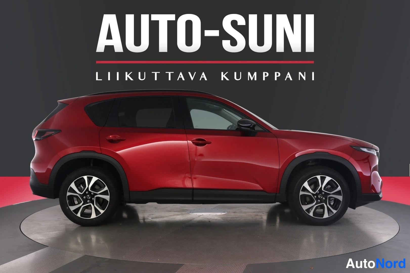 Etuviisto, nokka oikealle: Punainen Mazda CX-5 -mallinen auto sivulta kuvattuna studiossa, vasen kylki ja keula näkyvät.