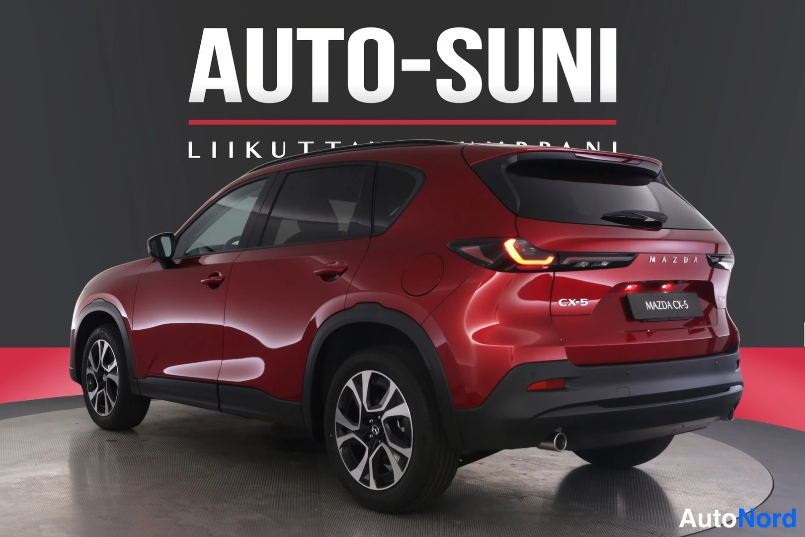 Takaviisto: Punainen Mazda CX-5 nähtynä takaa- ja sivusuunnasta, rekisterikilven paikalla MAZDA CX-5 -teksti, taustalla AUTO-SUNI-logo.