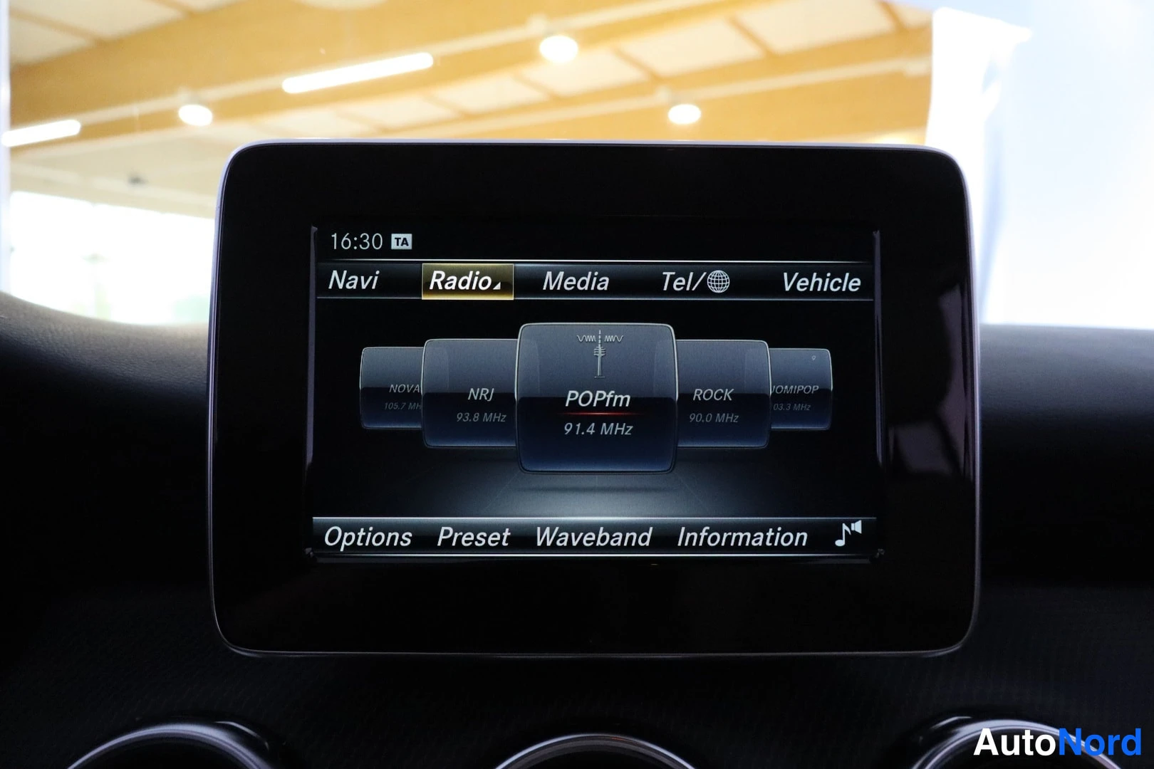 Etuviisto: Auton infotainment-näyttö radiovalikossa, asemana POPfm 91.4 MHz, valikot Navi, Radio, Media, Tel ja Vehicle.
