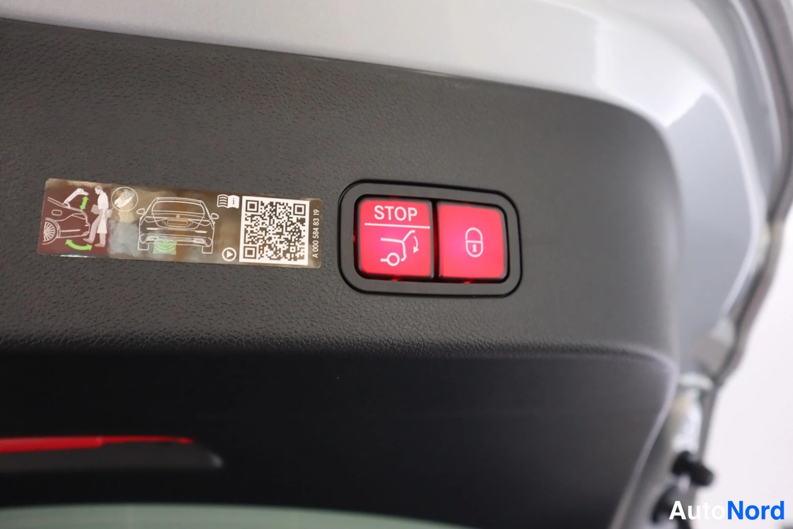 Muu: Takaluukun sisäpaneelin sähkötoimisen luukun painikkeet: punainen STOP-painike ja lukituspainike, vieressä QR-kooditarra.