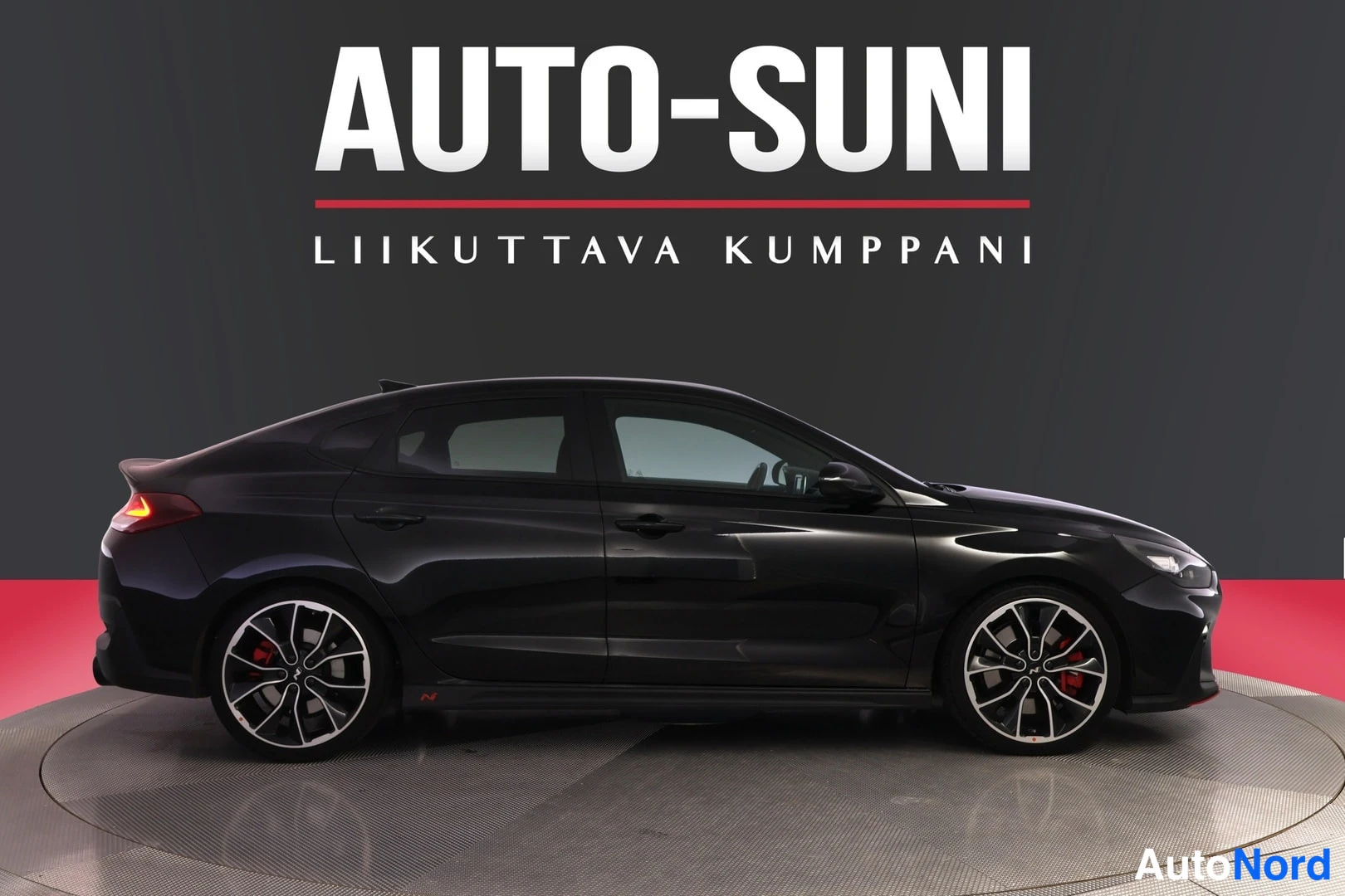 Sivulta: Mustan hatchbackin sivukuva vasemmalta. Pyörissä punaiset jarrusatulat.