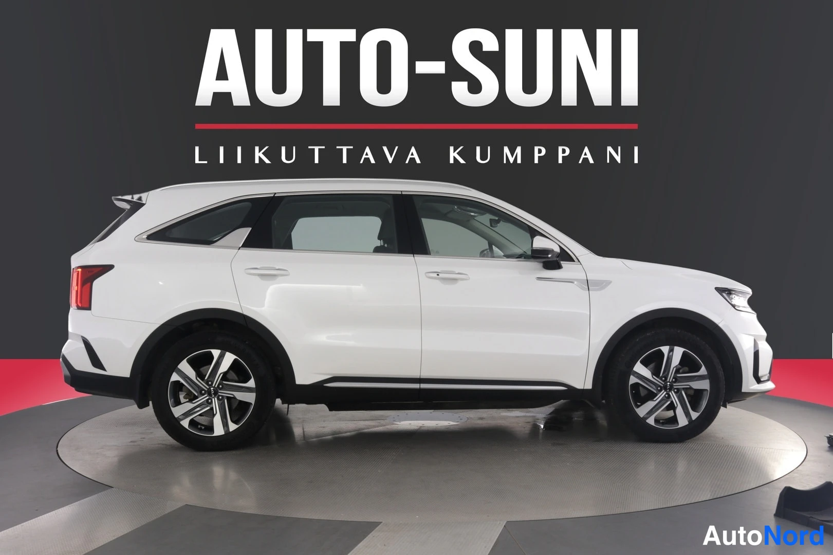 Sivulta: Valkoisen Kia Sorento -maasturin sivukuva oikealta puolelta, hopeavanteet ja tummat ikkunakehykset erottuvat kuvastudio-alueella.