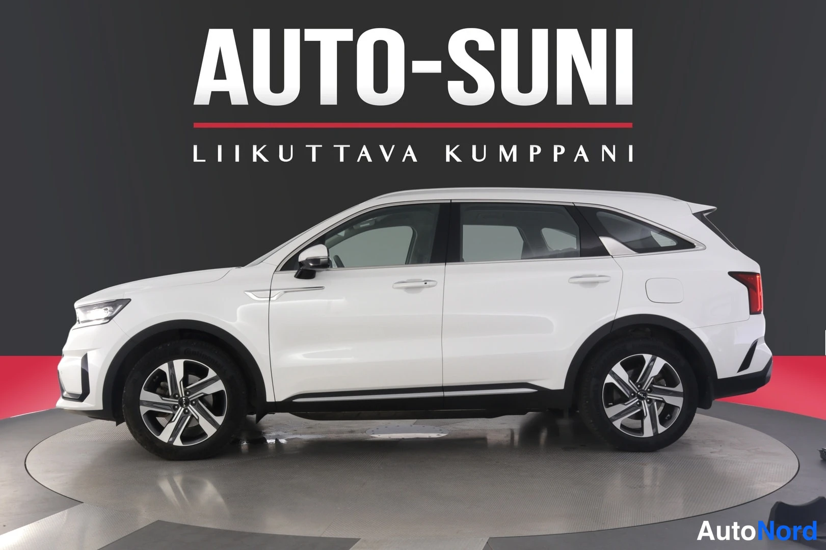 Sivulta: Valkoinen SUV näkyy kokonaan profiilinäkymänä, jossa katto ja sivupaneelit ovat selkeästi erottuvia. Auton renkaat ovat metallivanteiset ja valkoisessa ruudussa