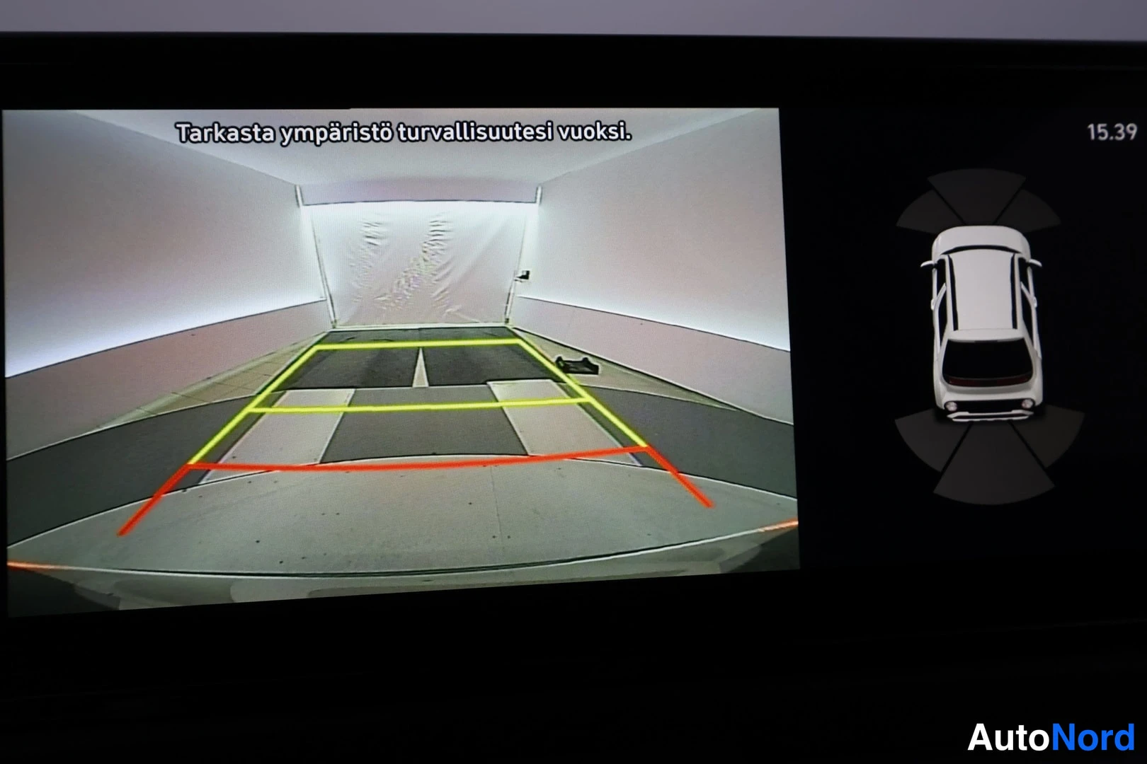 Muu: Infotainment screen displaying reverse camera view with yellow and red dynamic guidance lines overlaying a tiled floor background. Right side shows a top-down 3