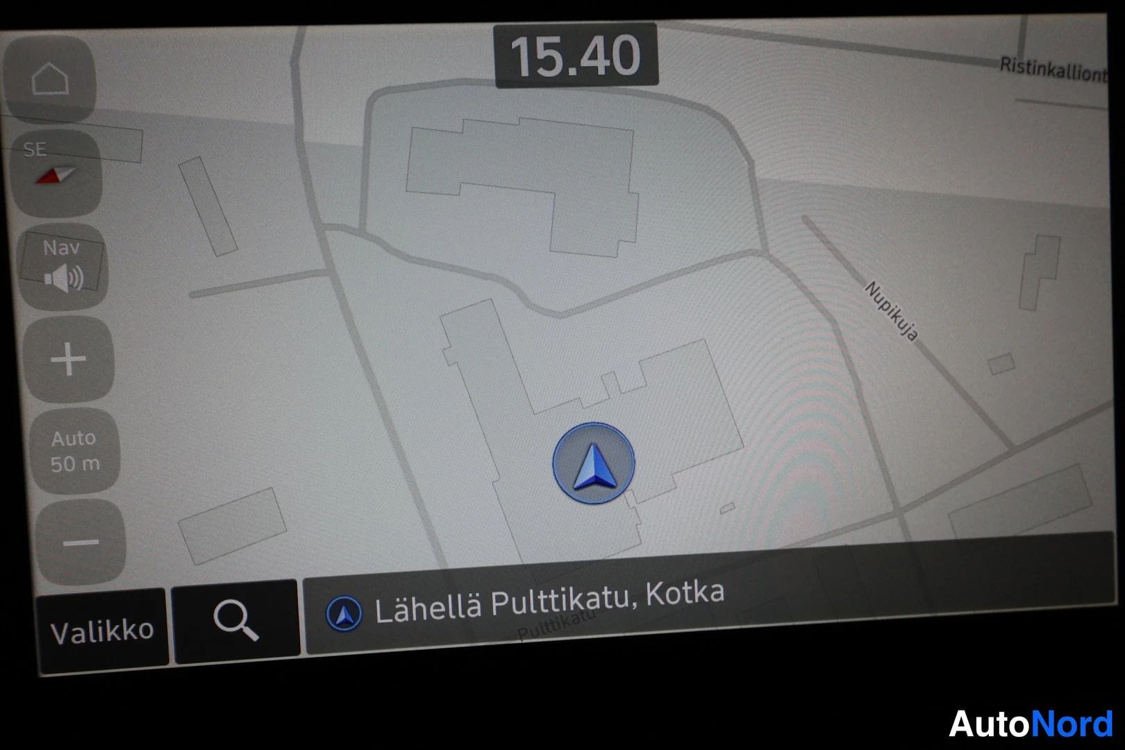Muu: Infotainment touchscreen displaying a navigation map interface. A blue arrowhead icon marks current position. The bottom bar shows the destination hint 'Lähellä