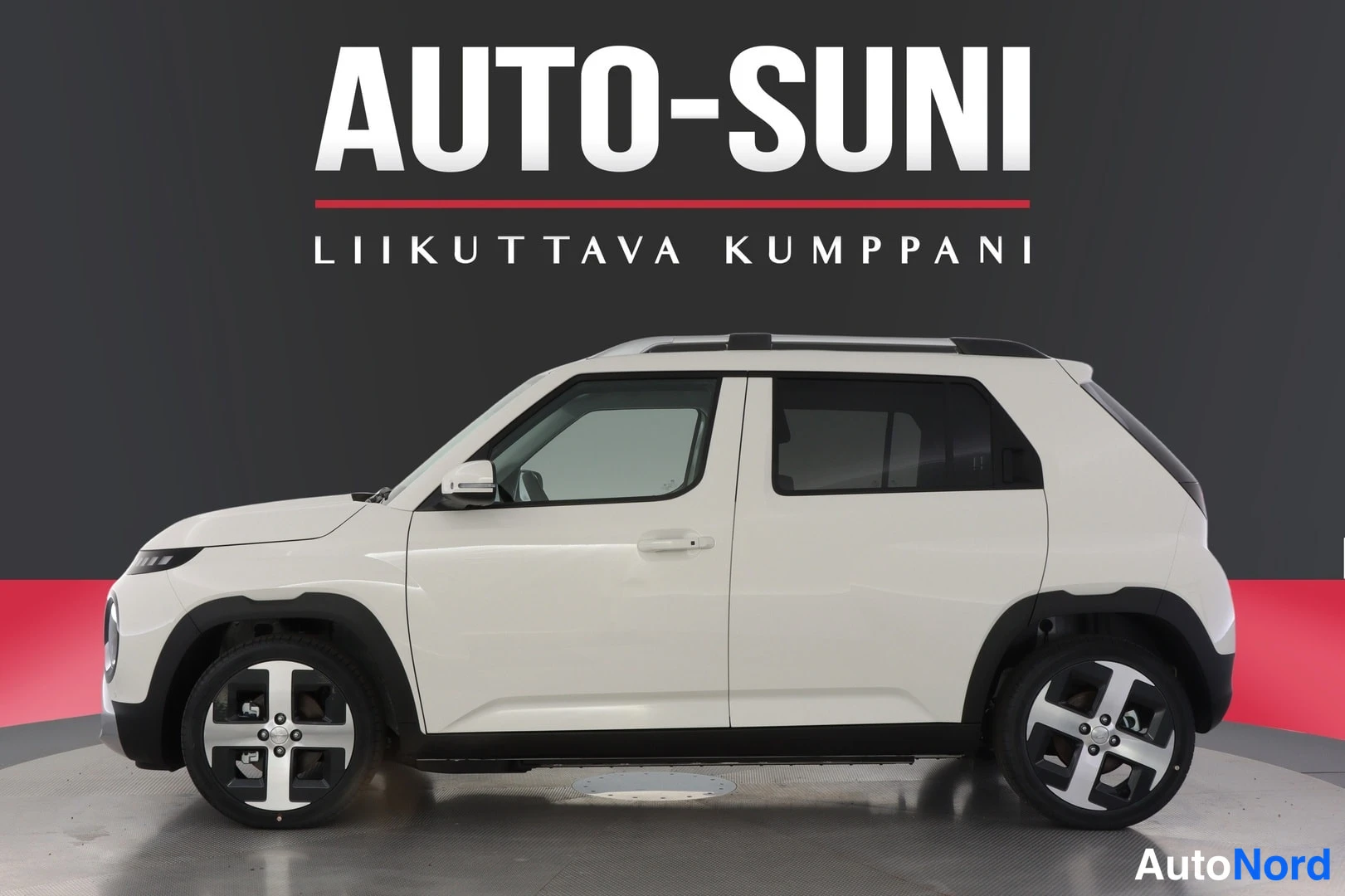 Sivulta: Hyundai Inster - Farmisinew valge kapott autol, kliendiboksis punase-must taustaga ja AUTO-SUNI logoga.