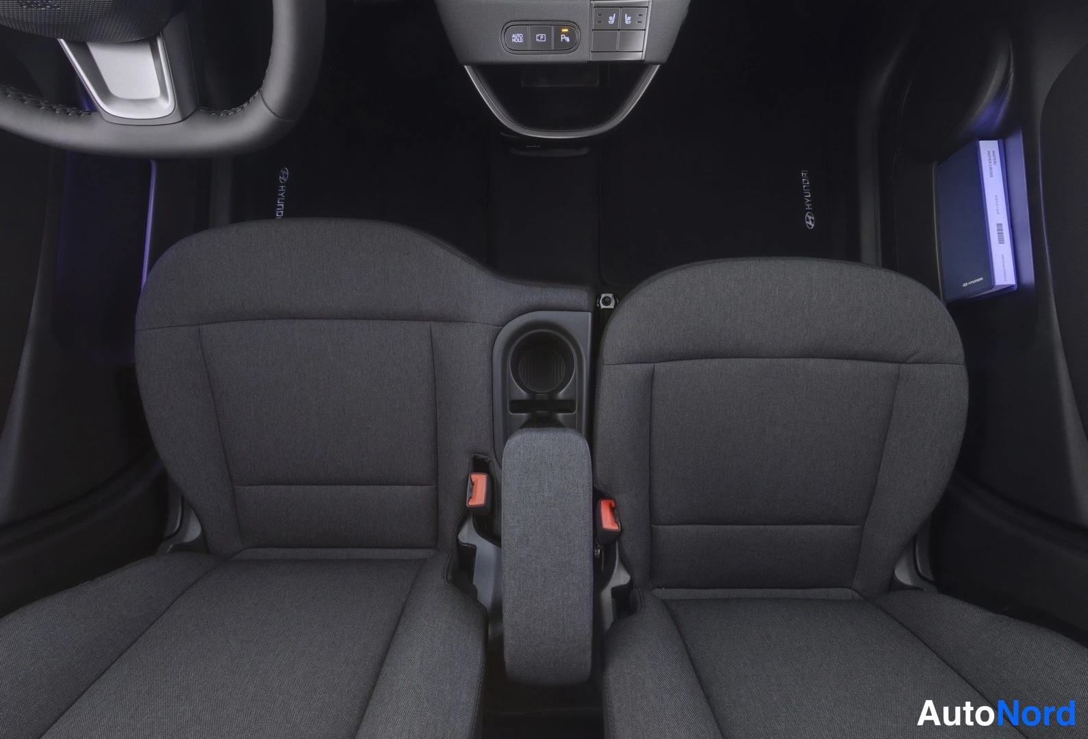 Etuistuimet: Front cabin shot from above showing two gray cloth front seats with orange ISOFIX clips visible on the inner sides, a central armrest console between them, and