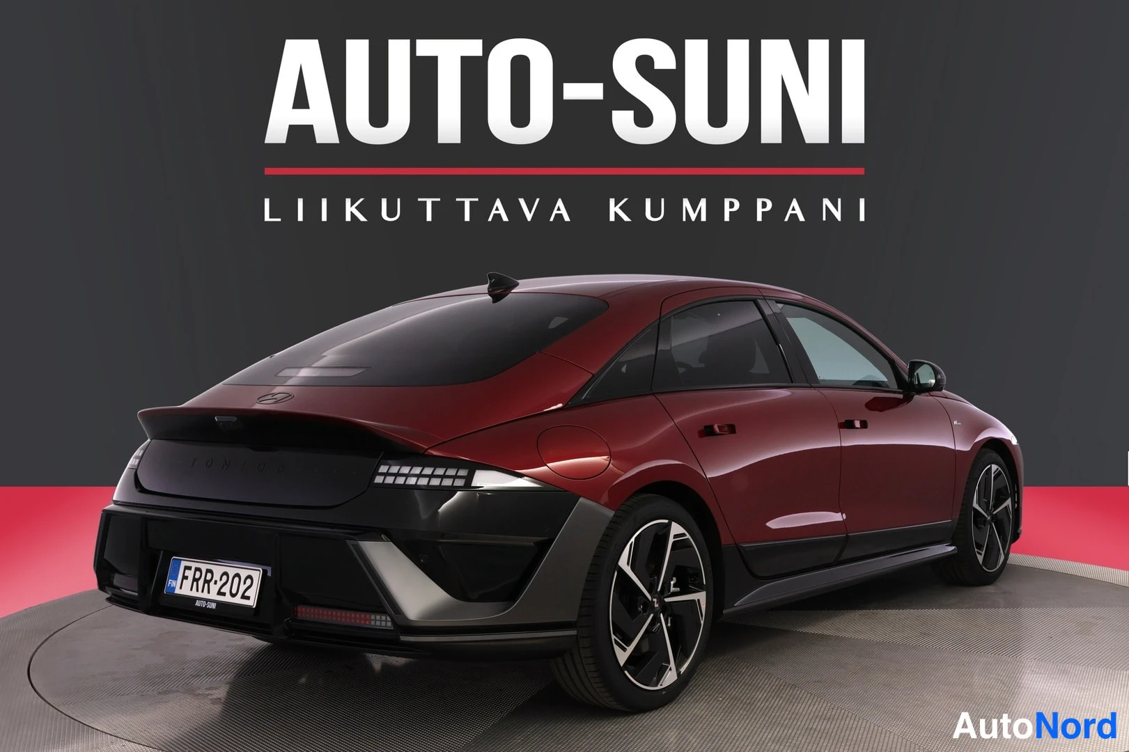 Takaviisto: Punaisen auton takakolmeneljännesnäkymä, takapää vasemmalla, rekisterikilpi.