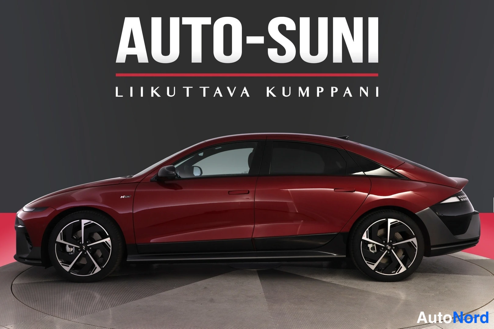 Sivulta: Punaisen auton sivukuva studiotyttä, taustalla AUTO-SUNI Liikuttava kumppani -teksti.