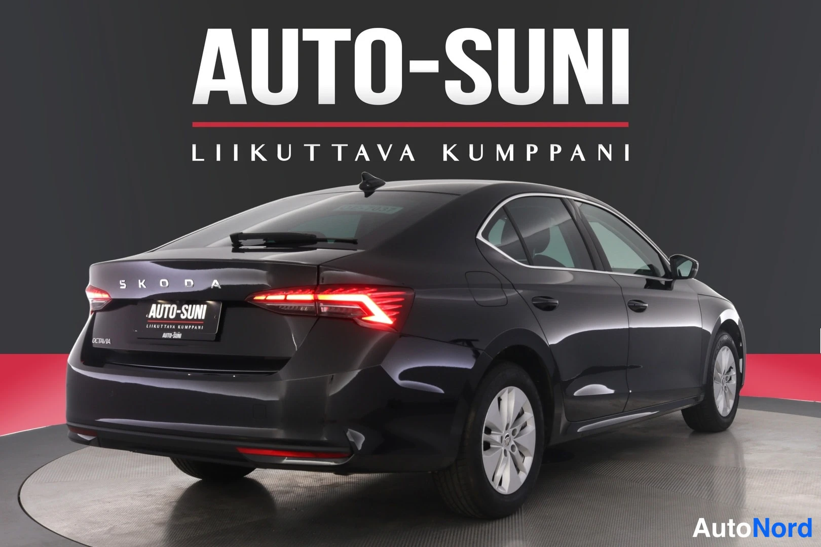 Takaviisto: Auton takakulma oikealta: mustan sedanin takamootti, takavalo ja takaospuskuri näkyvät, takana teksti OCTAVIA WAGON 1.5 TSI 110 kW.