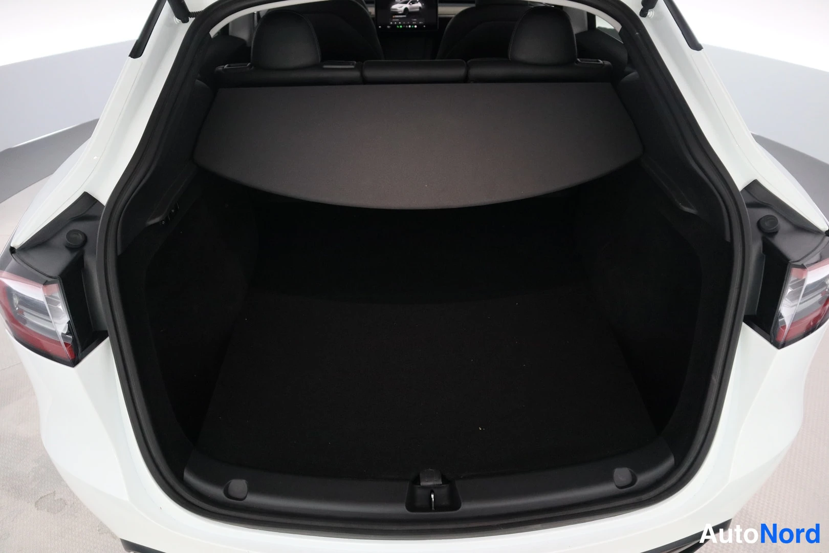 Tavaratila: Rear cargo area with open tailgate, black cargo cover deployed and rear seats folded down