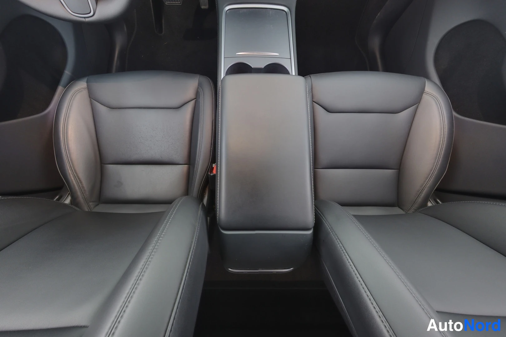 Etuistuimet: Close-up of black leather front seats with central armrest and rear cupholders