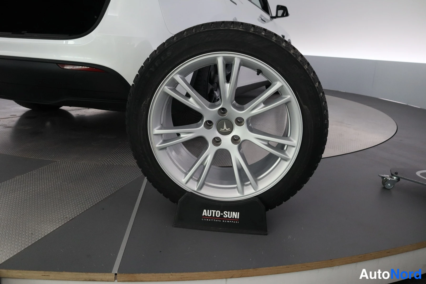 Sivulta: Side profile view showing silver alloy wheel fitted with winter tyre and Tesla logo hubcap