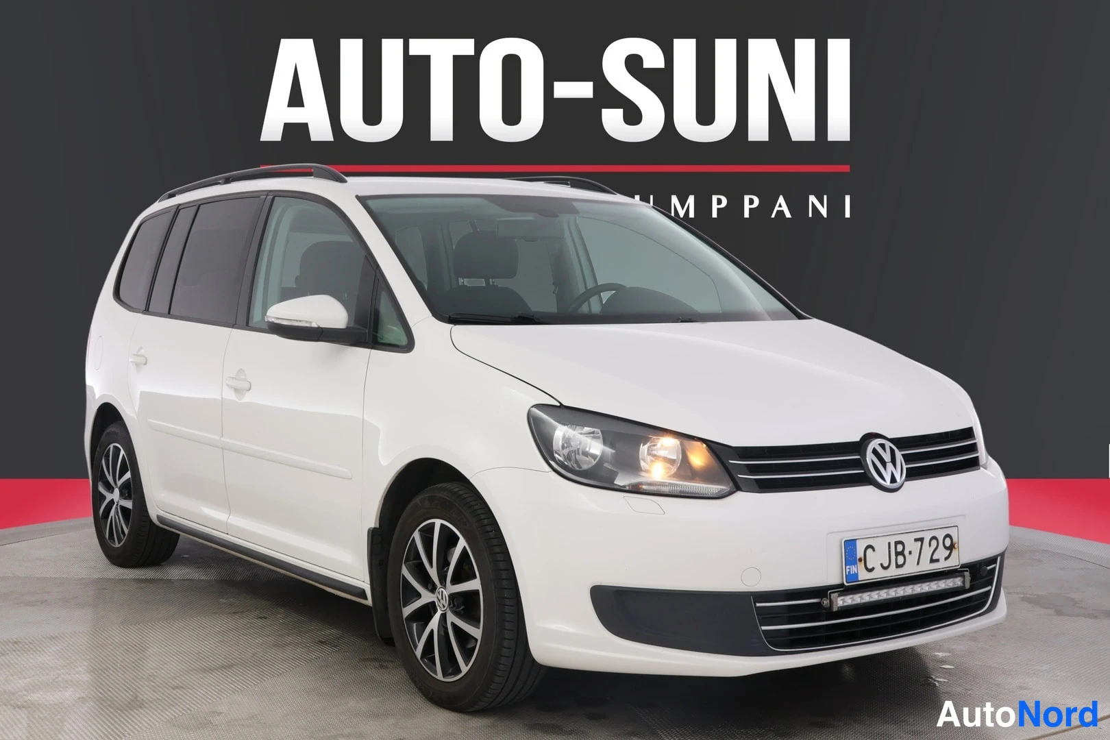 Etuviisto, nokka oikealle: Valkoinen Volkswagen-auto, jossa on etupaneeli ja oikea sivupaneeli näkyvissä. Auto on kuvattu studio-olosuhteissa, ja sen takavalot ovat kytketty.