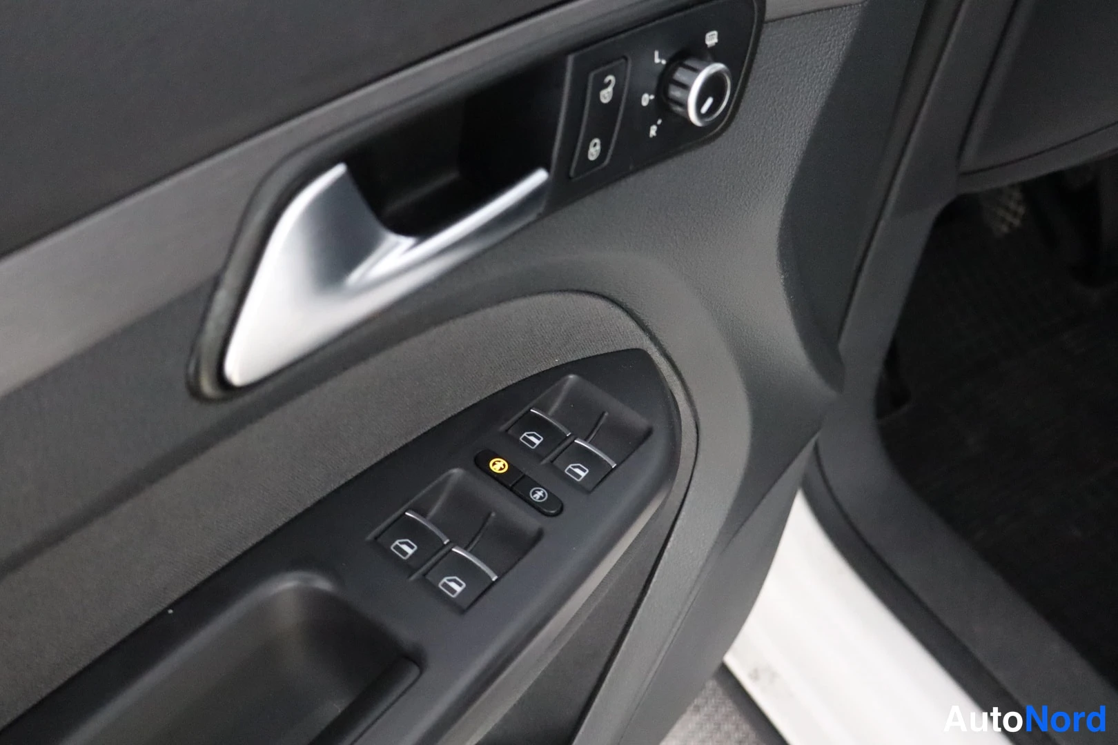 Yksityiskohta: Close-up of driver's door panel with window switches, mirror adjustment knob, and door handle