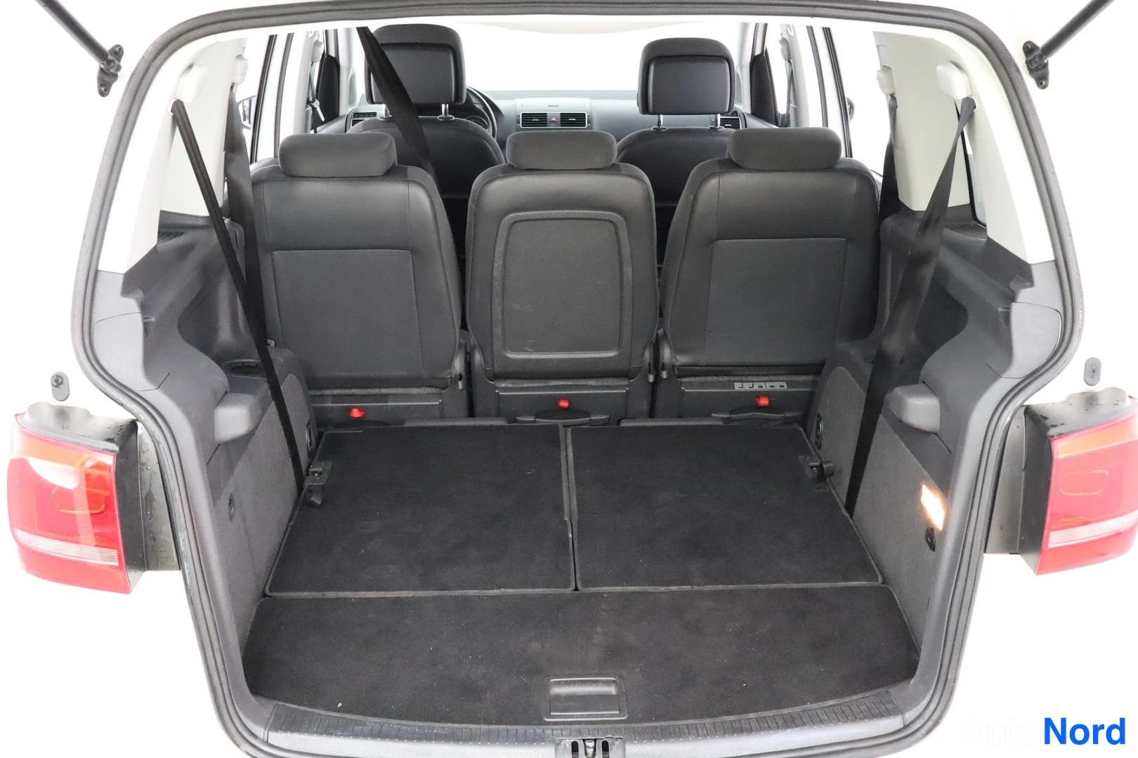 Tavaratila: View from the open boot door showing three second-row passenger seats in an upright position behind two rows of cargo space. All seats are upholstered in black