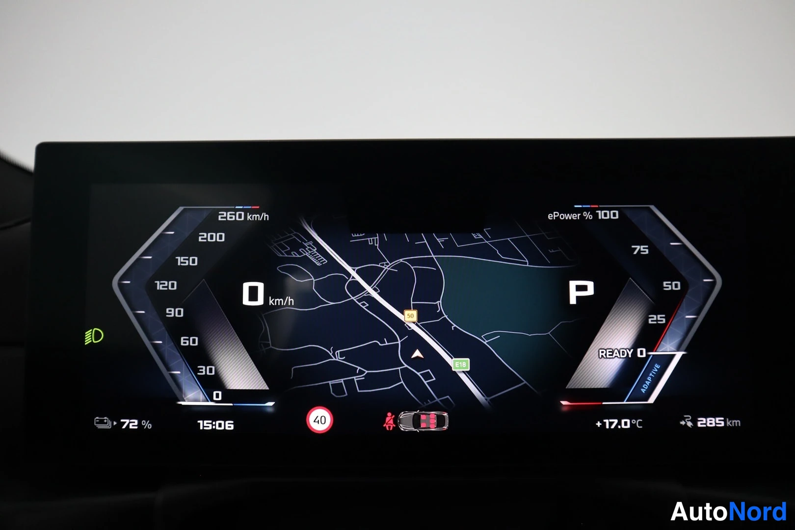 Yksityiskohta: Digitaalinen kuljettajan näyttö: nopeus 0 km/h, vaihde P, sähköteho 100 %, akku 72 %, toimintamatka 285 km ja keskellä navigointikartta.