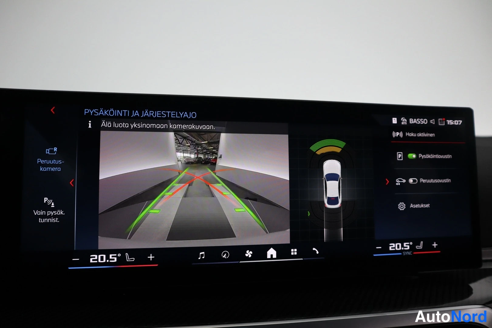 Ohjaamo: Close-up of the dashboard display showing the reverse camera with dynamic guidelines and parking assist graphics