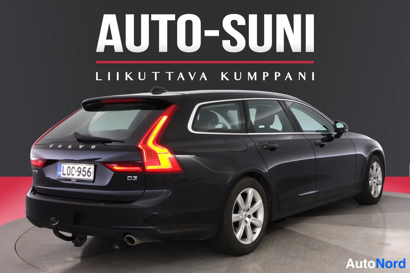 Takaviisto: Volvo V90 -farmarin takakulma kuvattuna vasemmalta, tummansininen koriteli, rekisteritunnus ja vetokoukku näkyvissä.