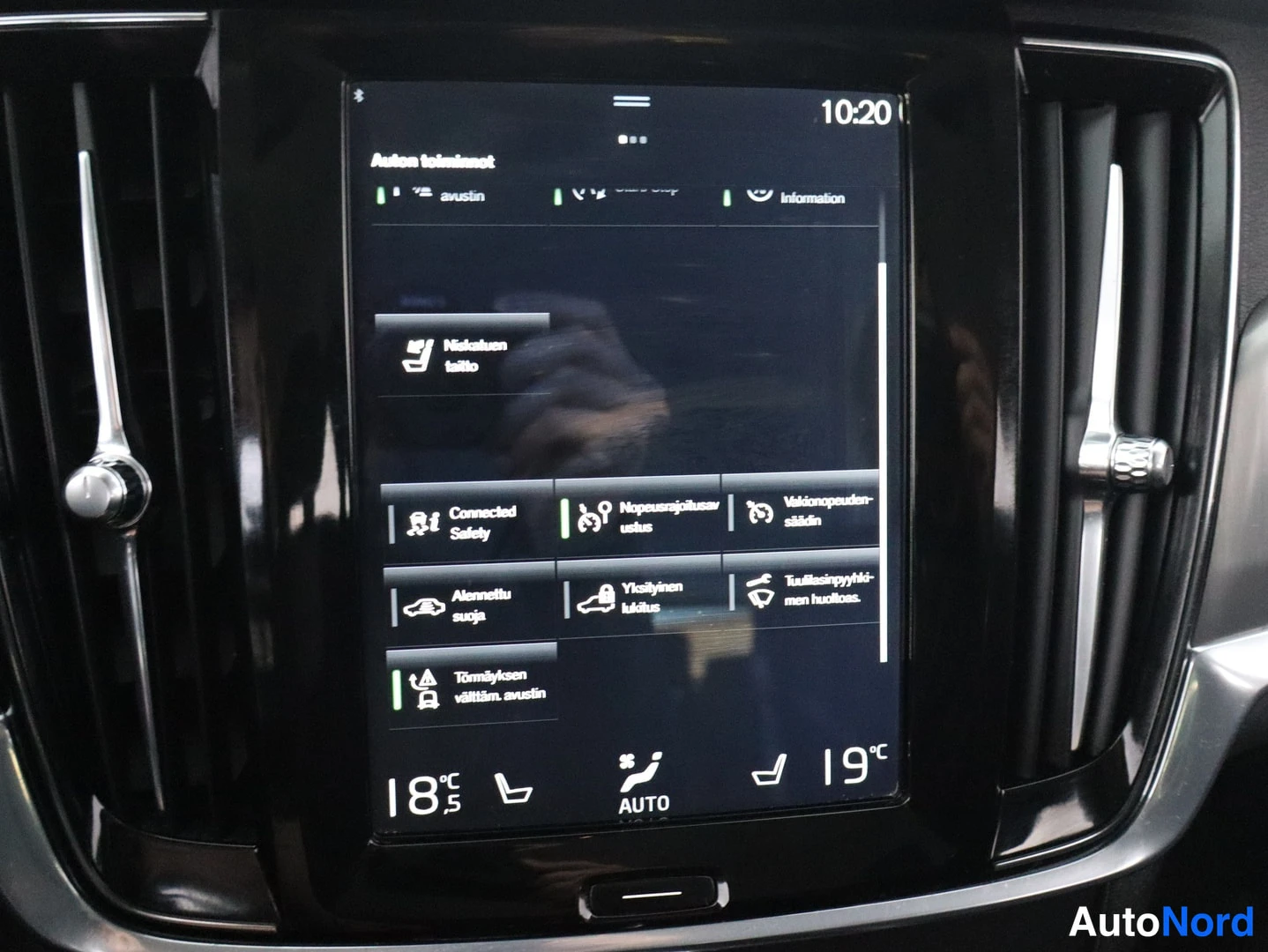 Yksityiskohta: Close-up of the central infotainment screen displaying a menu with Finnish text and seat heater controls.