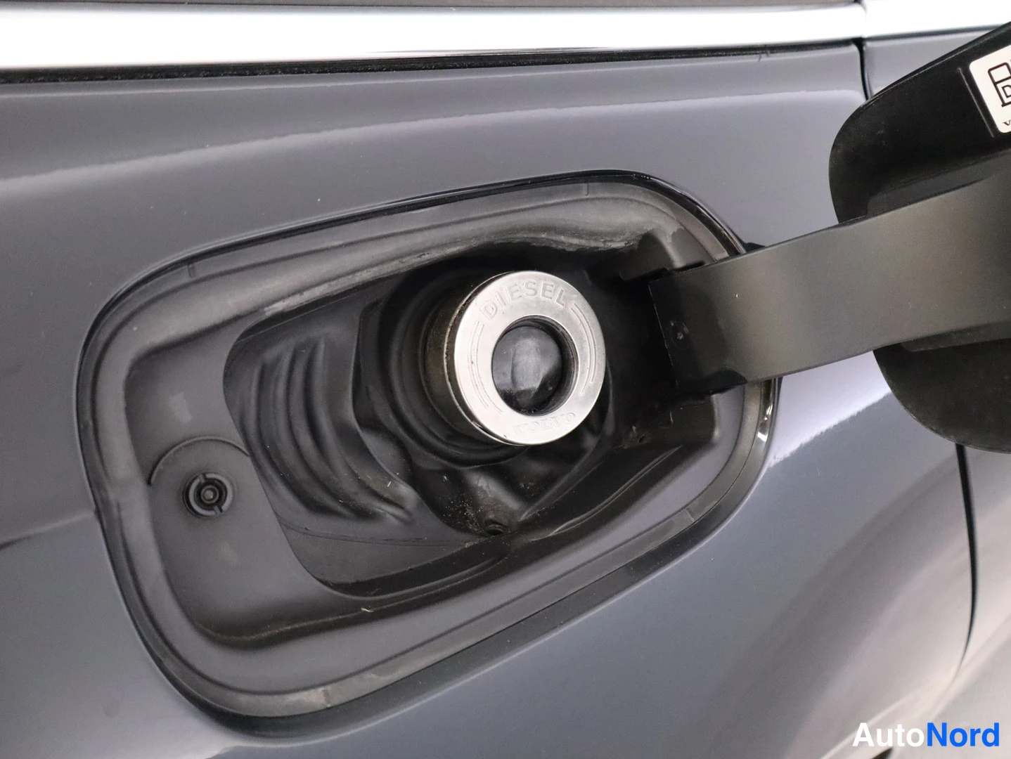 Yksityiskohta: Suljettu tankkiluukku lähikuvassa; polttoainesuuttimeen liitetyssä kannessa lukee DIESEL.
