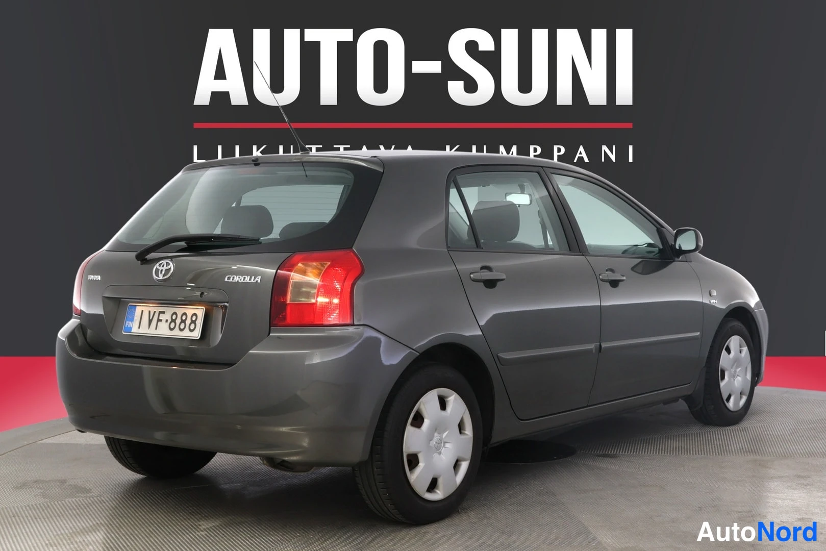 Takaviisto: Kuvassa harmaanharmaa Toyota Corolla -auton takapää ja oikea sivu. Takasäleikkö, Toyota-logo, 'COROLLA'-kirjoitus ja rekisterikilpi ovat selvästi nähtävissä.