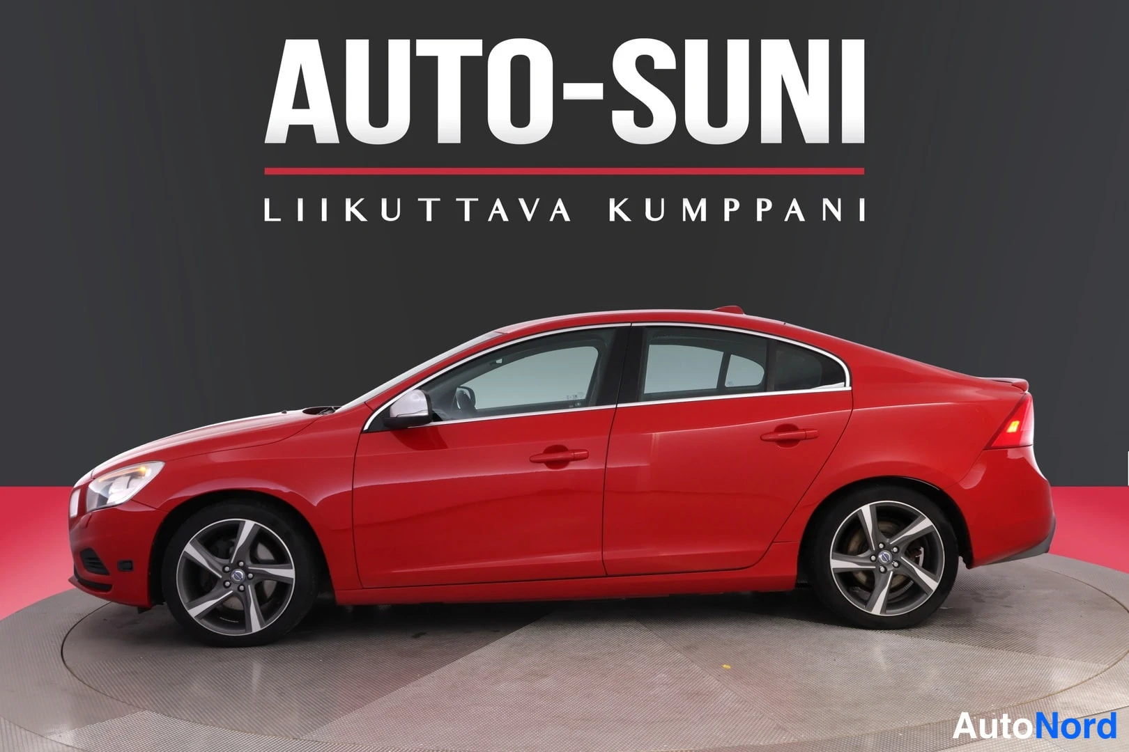 Sivulta: Punaisen sedanan sivuprofiili vasemmalta, kevytmetallivanteet näkyvissä.