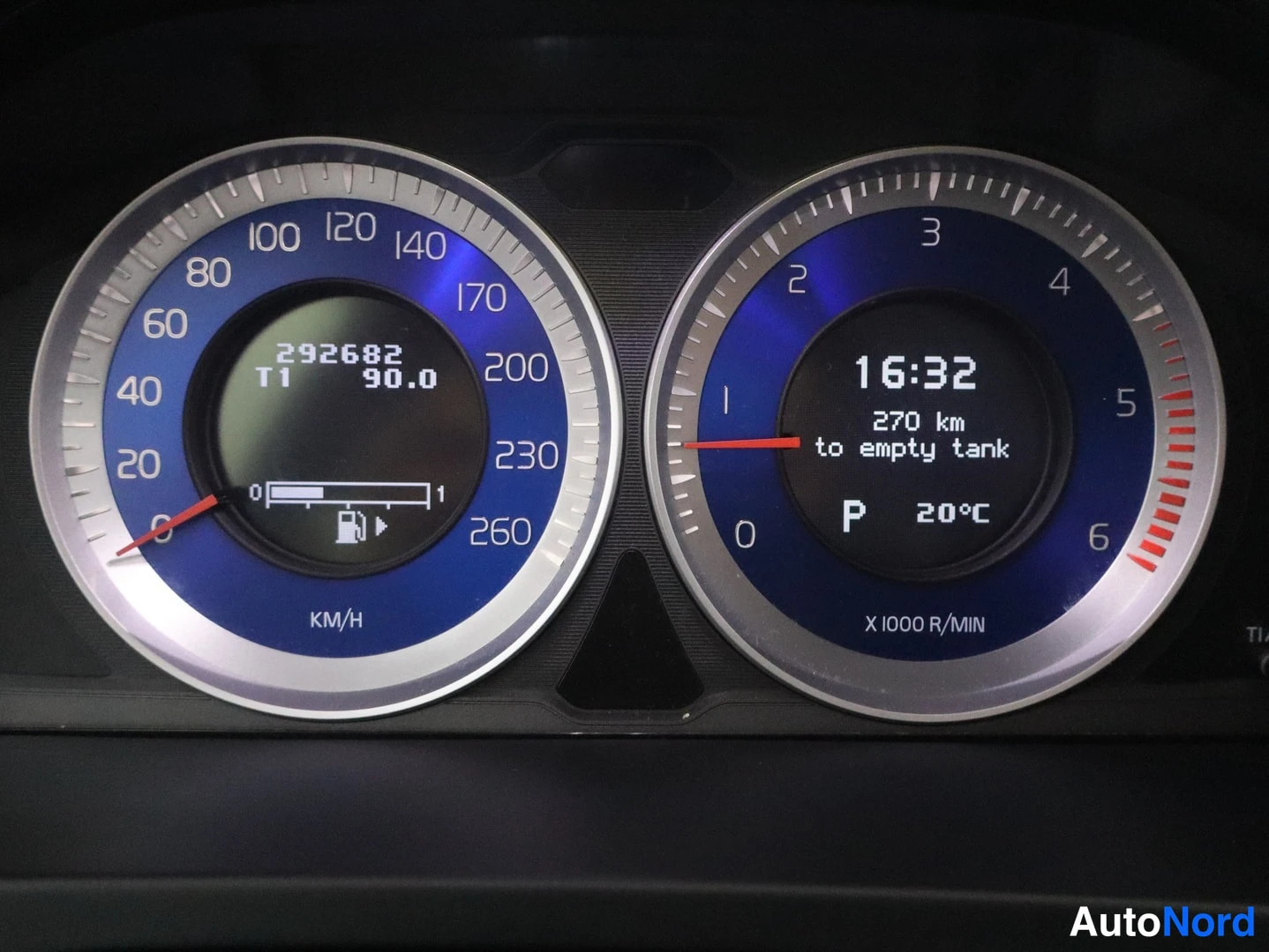 Muu: Volvo S60:n mittaristot lähiötä: nopeusmittari ja kierrosmittari sinisillä taustoilla, matkamittari 292682 km ja polttoaineindikaattori.
