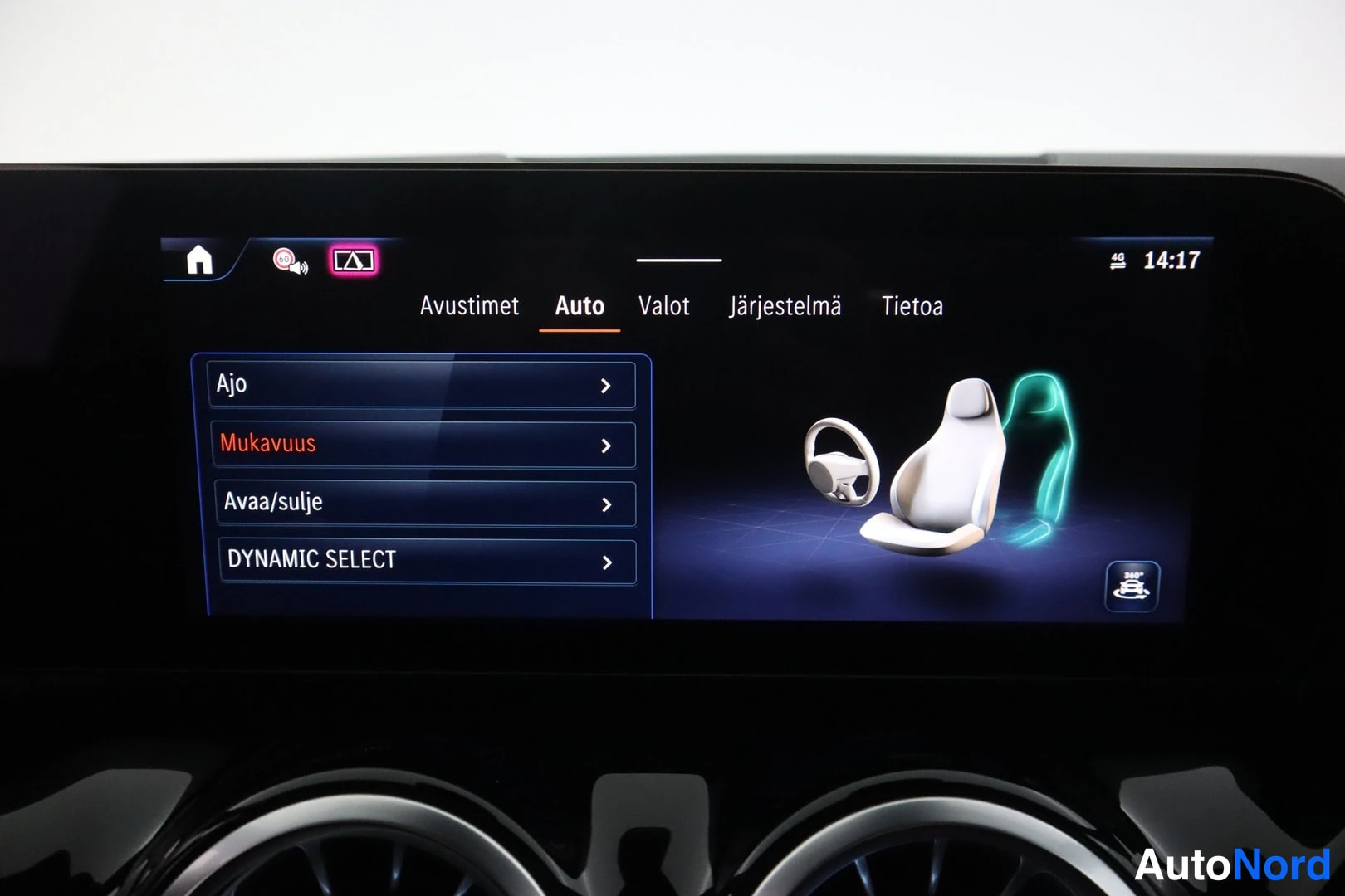 Yksityiskohta: Auton keskinäytön 'Auto'-valikko kohdilla Ajo, Mukavuus, Avaa/sulje ja DYNAMIC SELECT; oikealla kuvitus ohjauspyörästä ja istuimesta.
