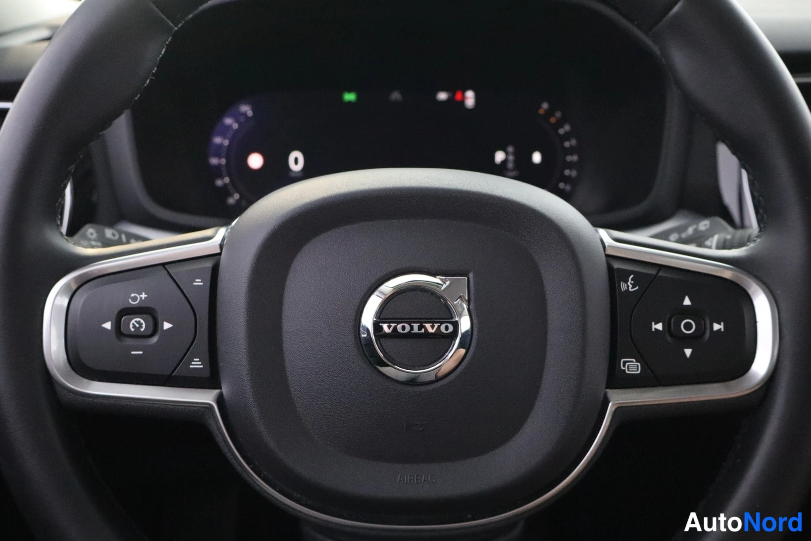 Edestä: Volvo-ohjauspyörän lähikuva keskuspalkineine merkkeineen ja monitoimapainikkeineen.