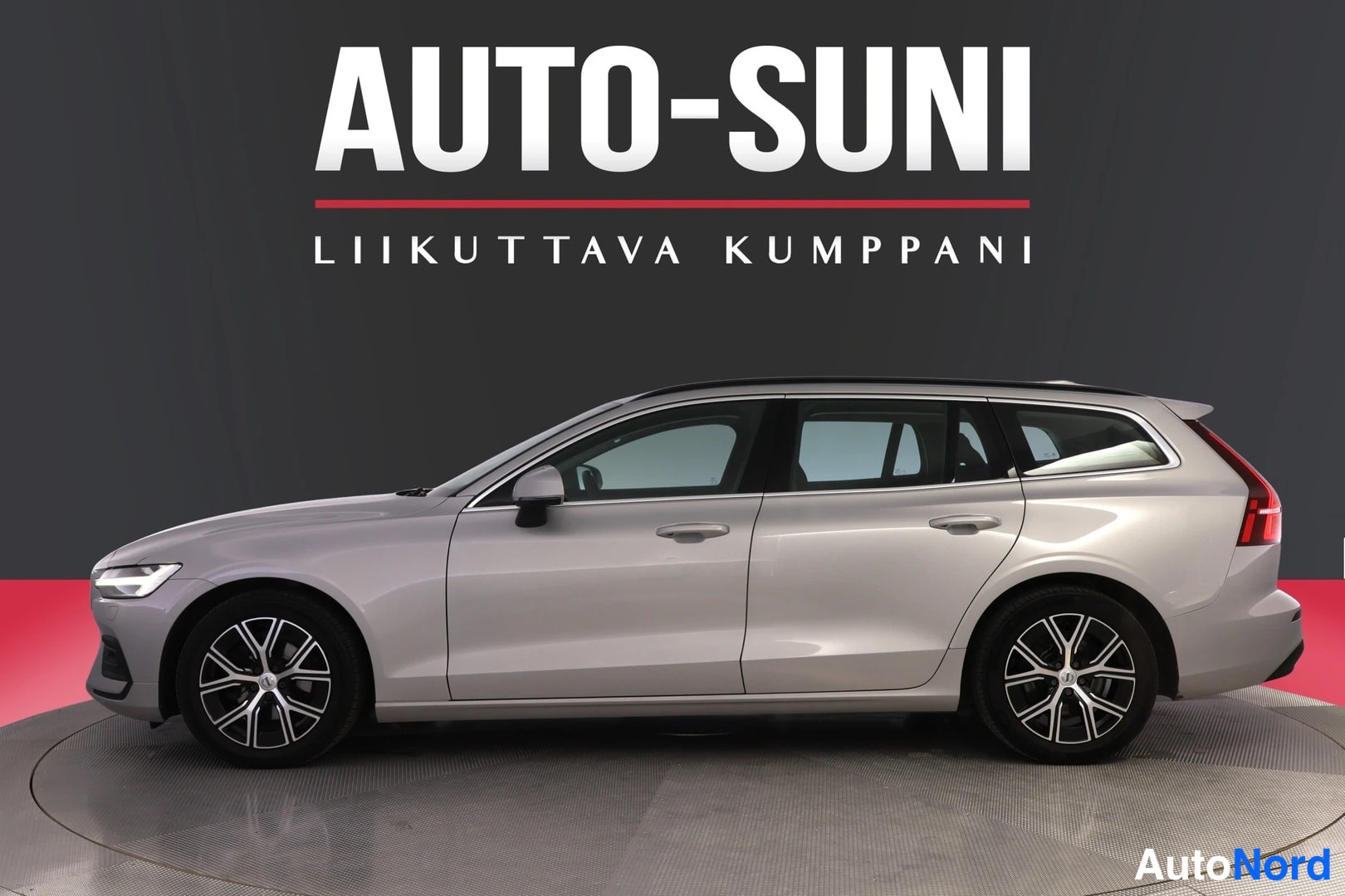 Sivulta: Auton kylki ja keulan kulma kuvattuna vasemmalta; hopeanvärinen farmariauto tummassa studiossa.