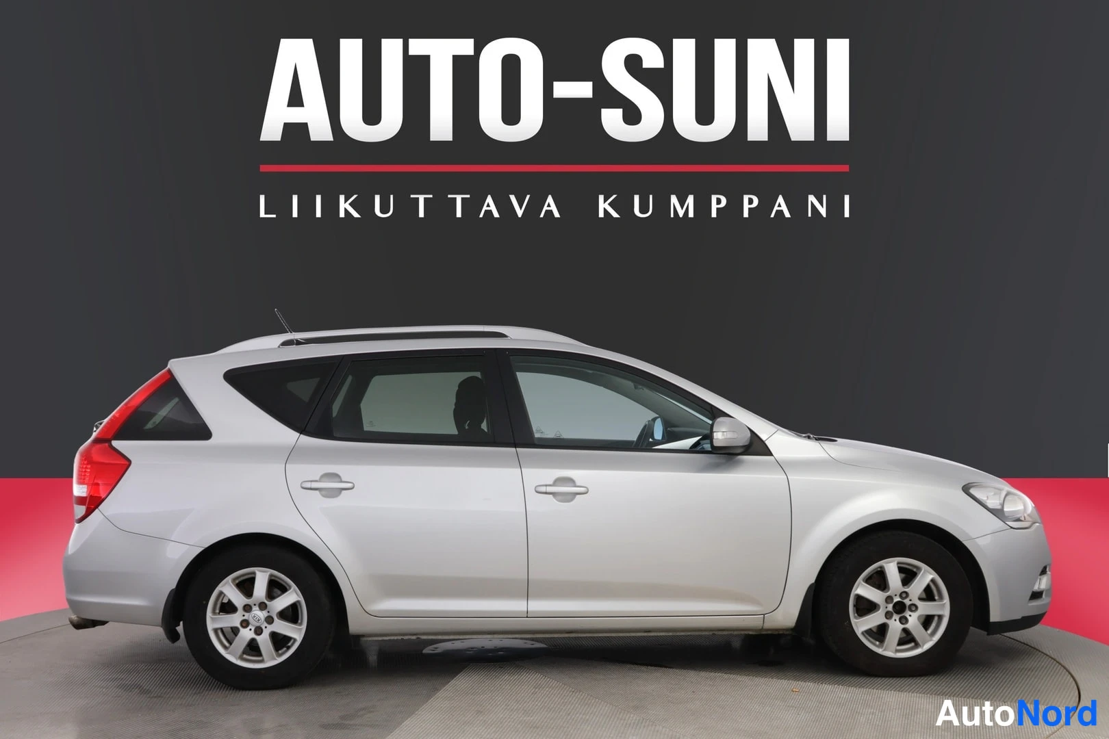 Etuviisto, nokka oikealle: Hopeanharmaa farmariauto sivulta kuvattuna tummaa studio­taustaa vasten, keula kuvan oikeassa reunassa; näkyvissä ovet, ikkunat, kattokaaret ja hopeanvär