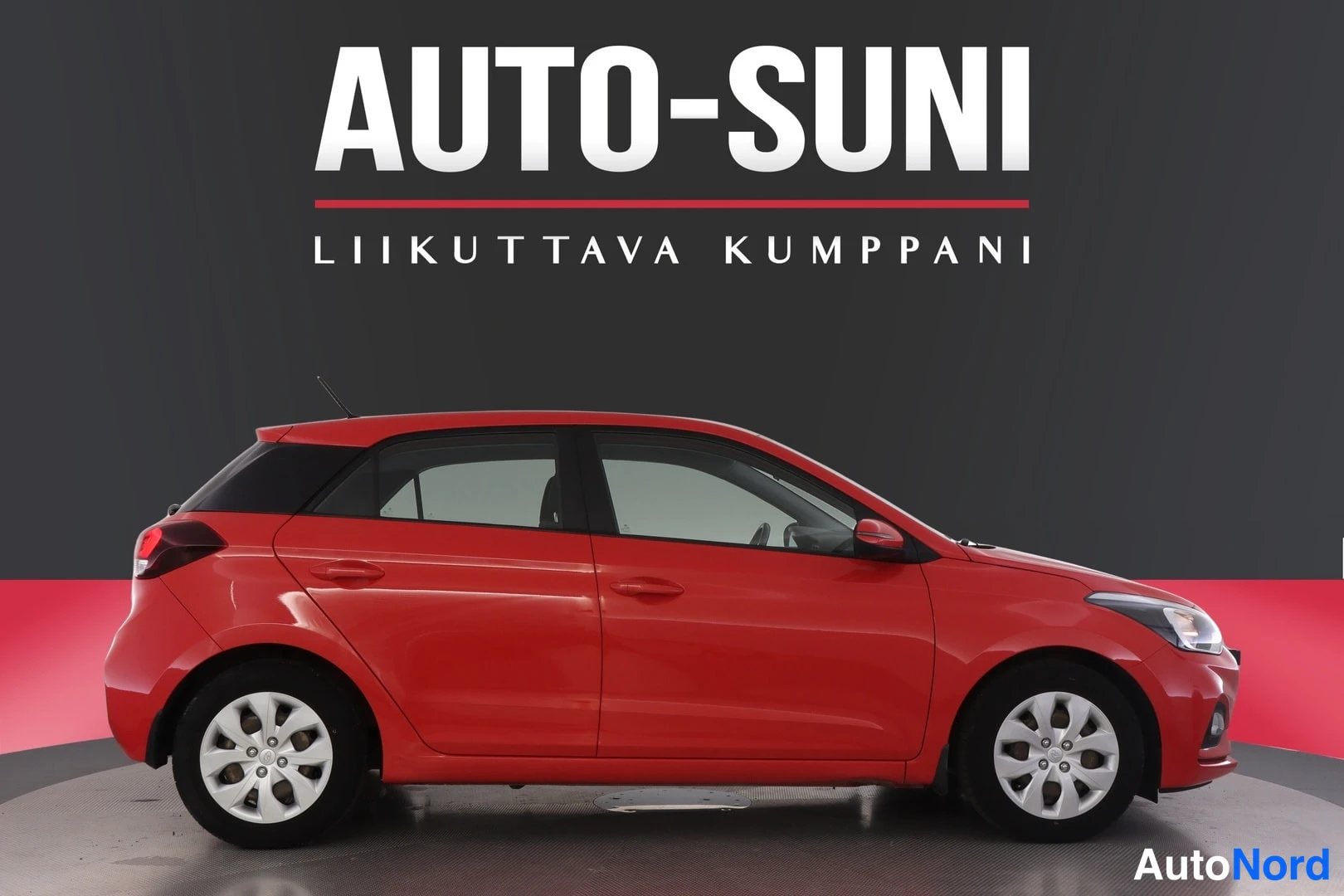 Sivulta: Punaisen Hyundai i20:n sivukuva oikealta puolelta, viisiovinen hatchback, hopeavanteet.