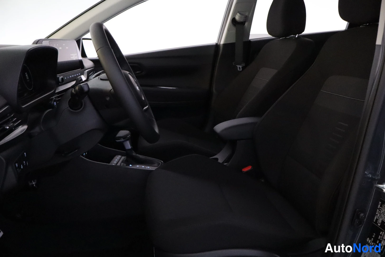 Yksityiskohta: Sisätilat: Hyundai BAYON 1.0 T-GDi Comfort Plus Edition 2026, sisätilat, eturivin istuimet ja ohjaamo. Mustat kangasistuimet, ohjauspyörä, keskikonsolirivi, kos