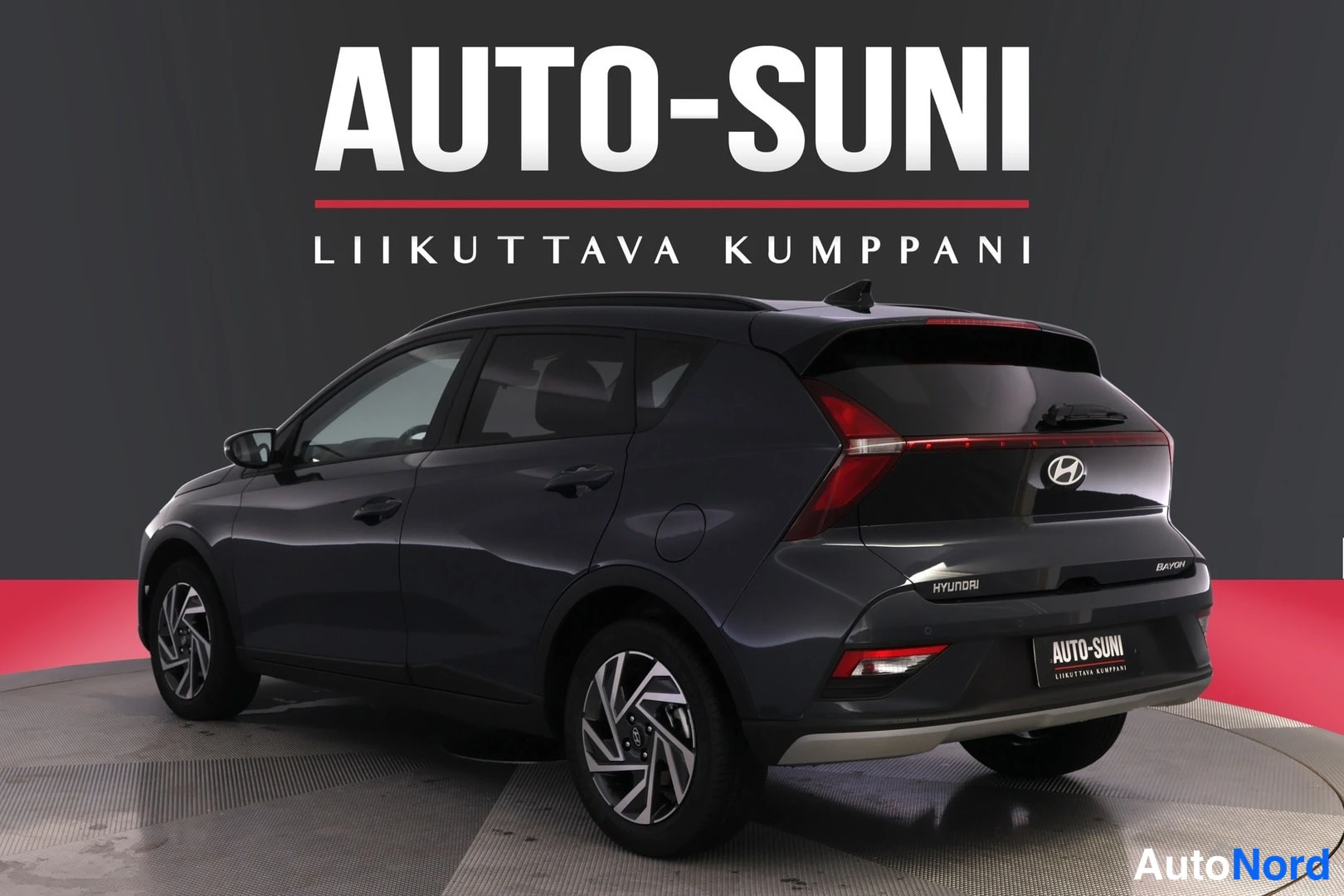 Takaviisto: Hyundai Bayon -henkilöauto takaa oikealta kolmannelta kulmalta kuvattuna studiossa; takaluukussa Bayon-merkintä.