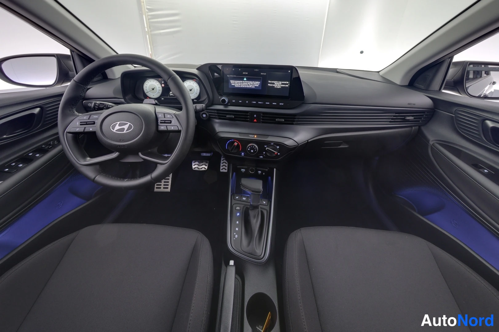 Muu: Hyundai Bayonin ohjaamo etuosalta nähtynä: multifunktioinen ohjauspyörä, analogiset mittarit, keskikonsolin infotainment-näyttö ja automaattivaihteiston valitsi